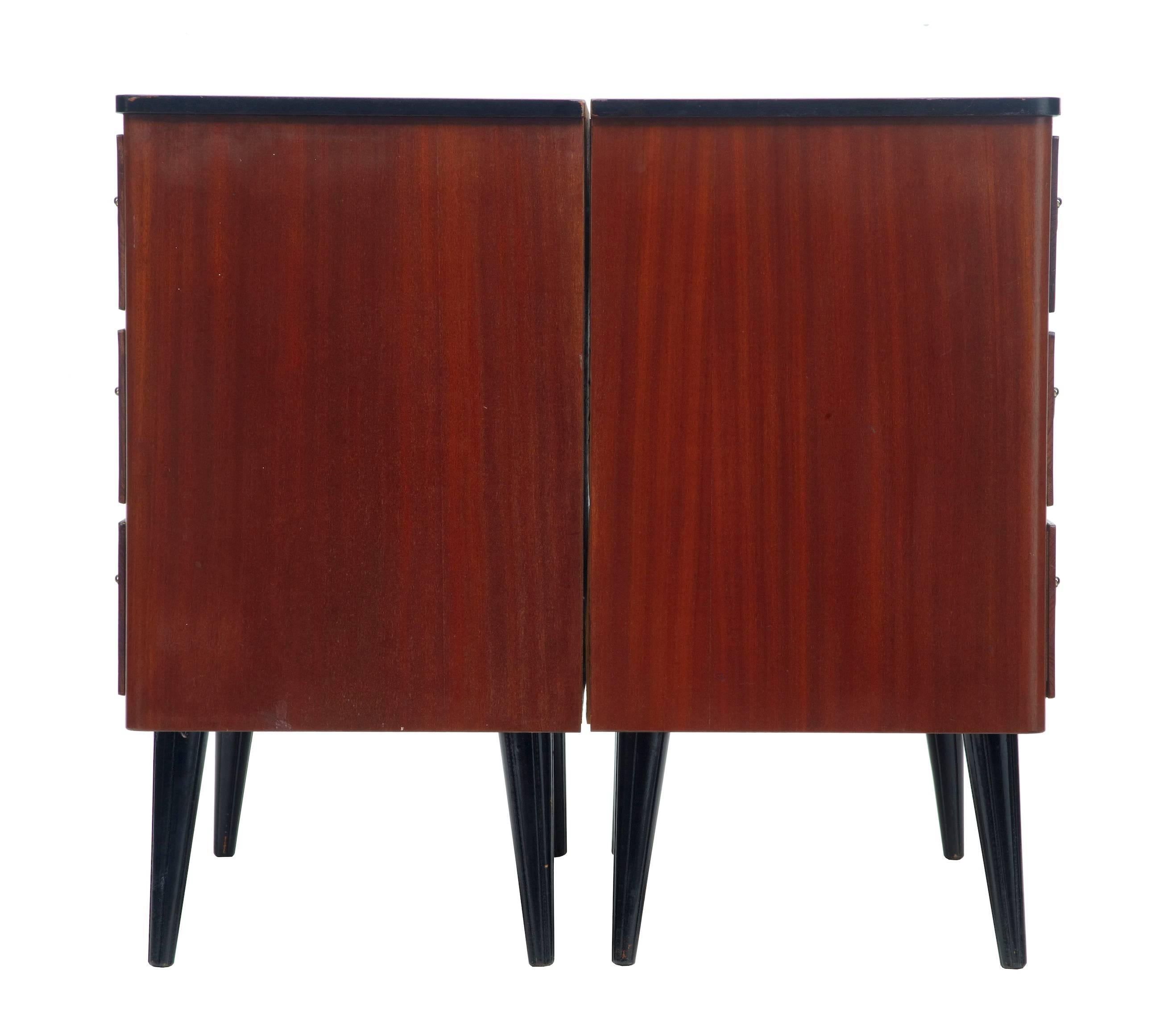 Pair of teak Danish chest of drawers, circa 1960.
Three drawer chests with brass handles and escutcheons.
Standing on ebonised tapering legs.

Measures: Height: 27 1/2