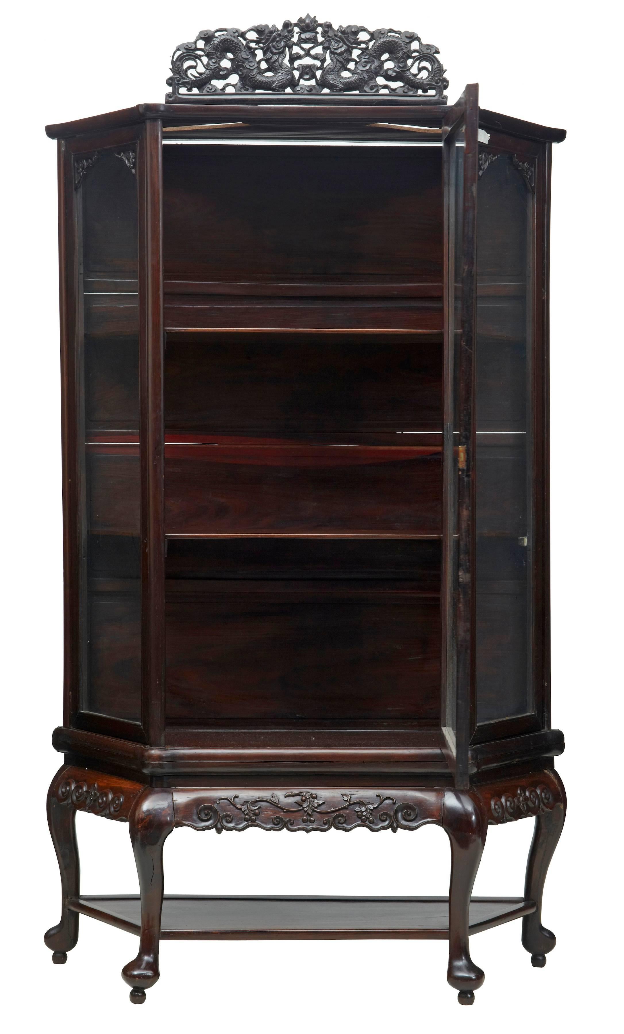 Late 19th century Chinese display cabinet, circa 1890.
Single large glazed door opens to two shelves, stands on four shaped legs united by a shelf.
Detachable pierced carving of dragons to the top, this would have been flanked either side by