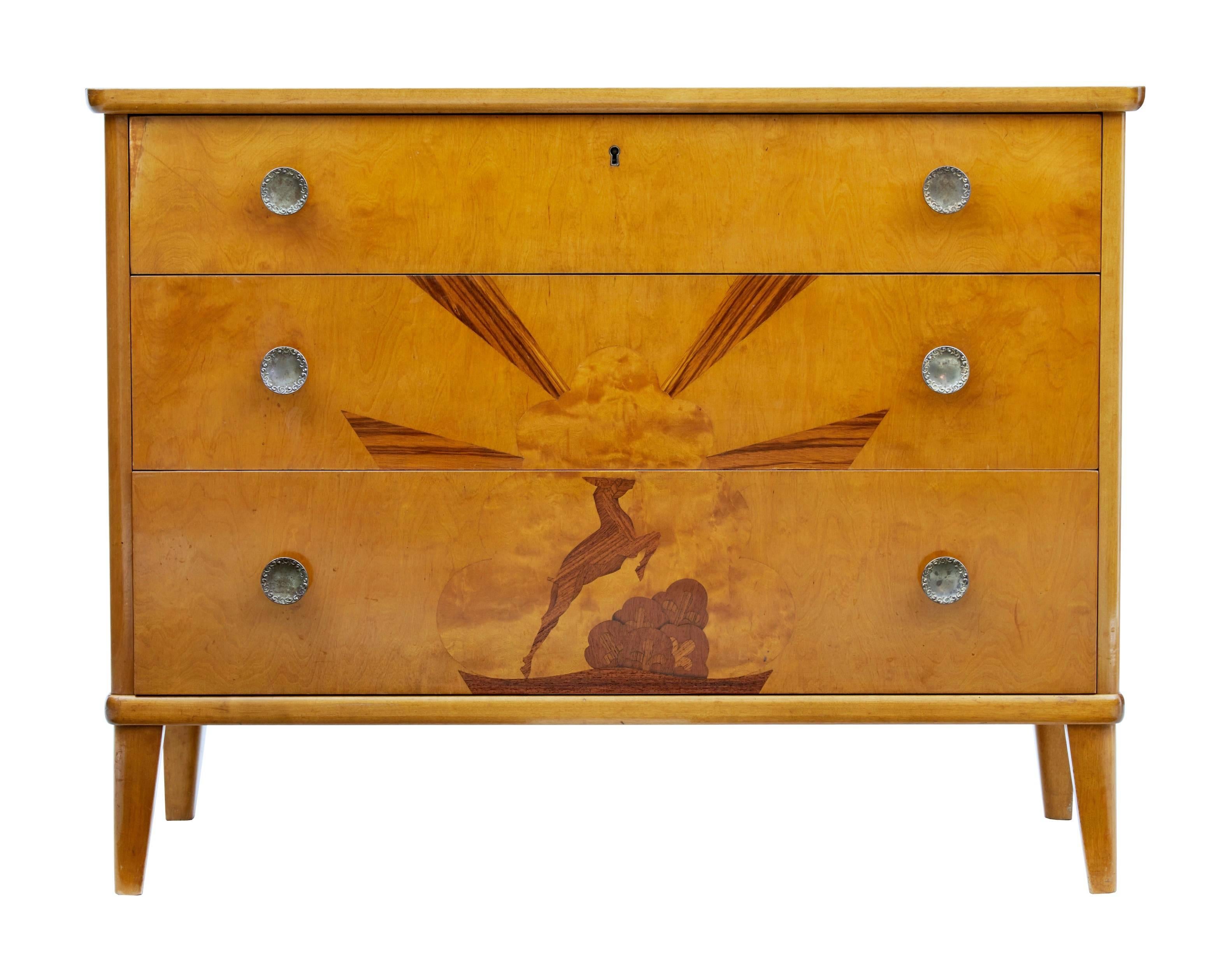 Late Art Deco Swedish birch chest of drawers, circa 1935.
Beautifully inlaid to the front in rosewood depicting a prancing stag and sunburst.
Three drawers with original handles.
Good rich birch color.
Minor surface marks in line with