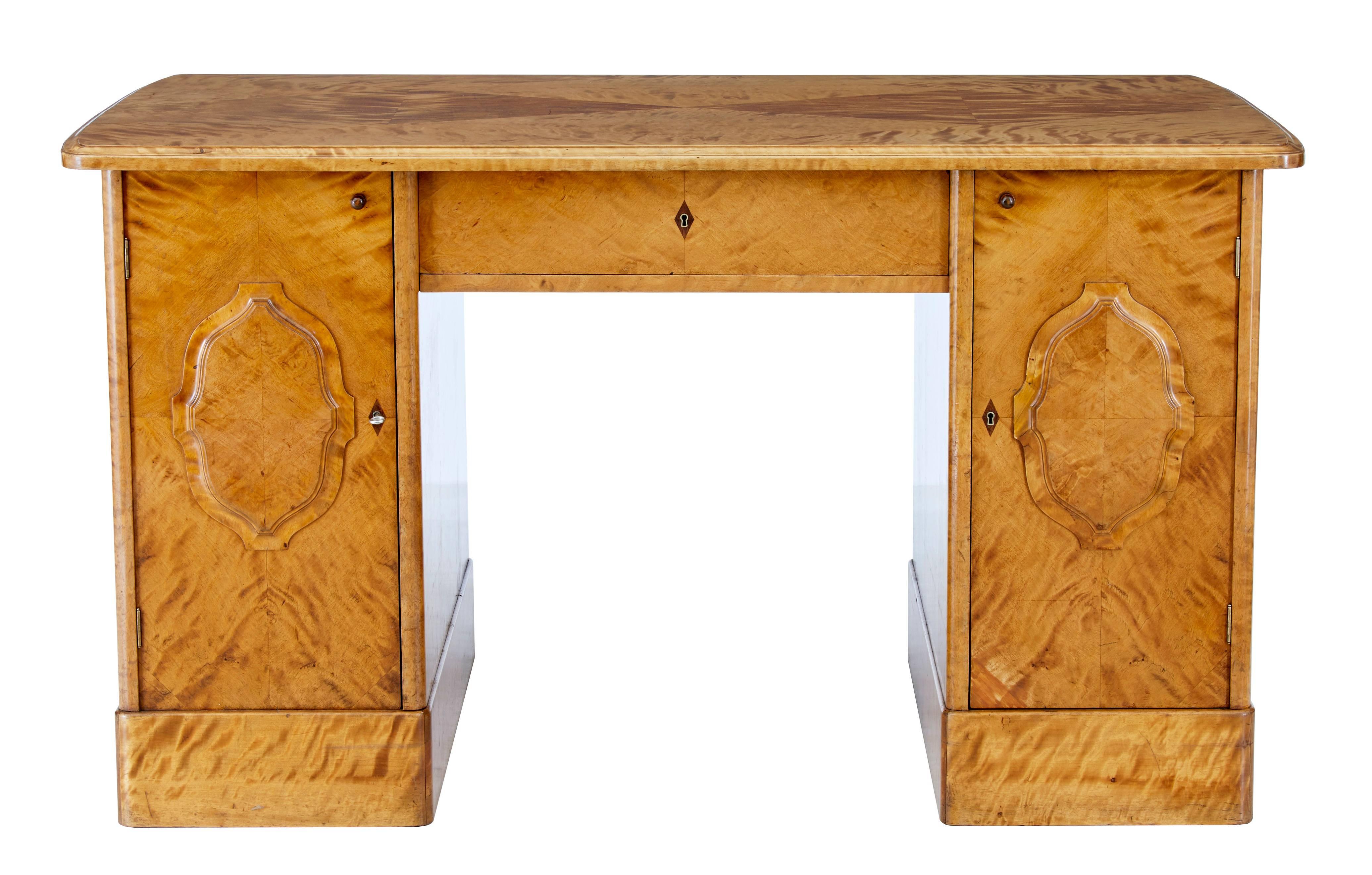 Pedestal desk in rich birch, circa 1910.
Two pedestals with removable central section and writing surface.
Each pedestal contains two shelves and two sliding drawers.
Standing on plinth base.
Age splits to top, but structurally