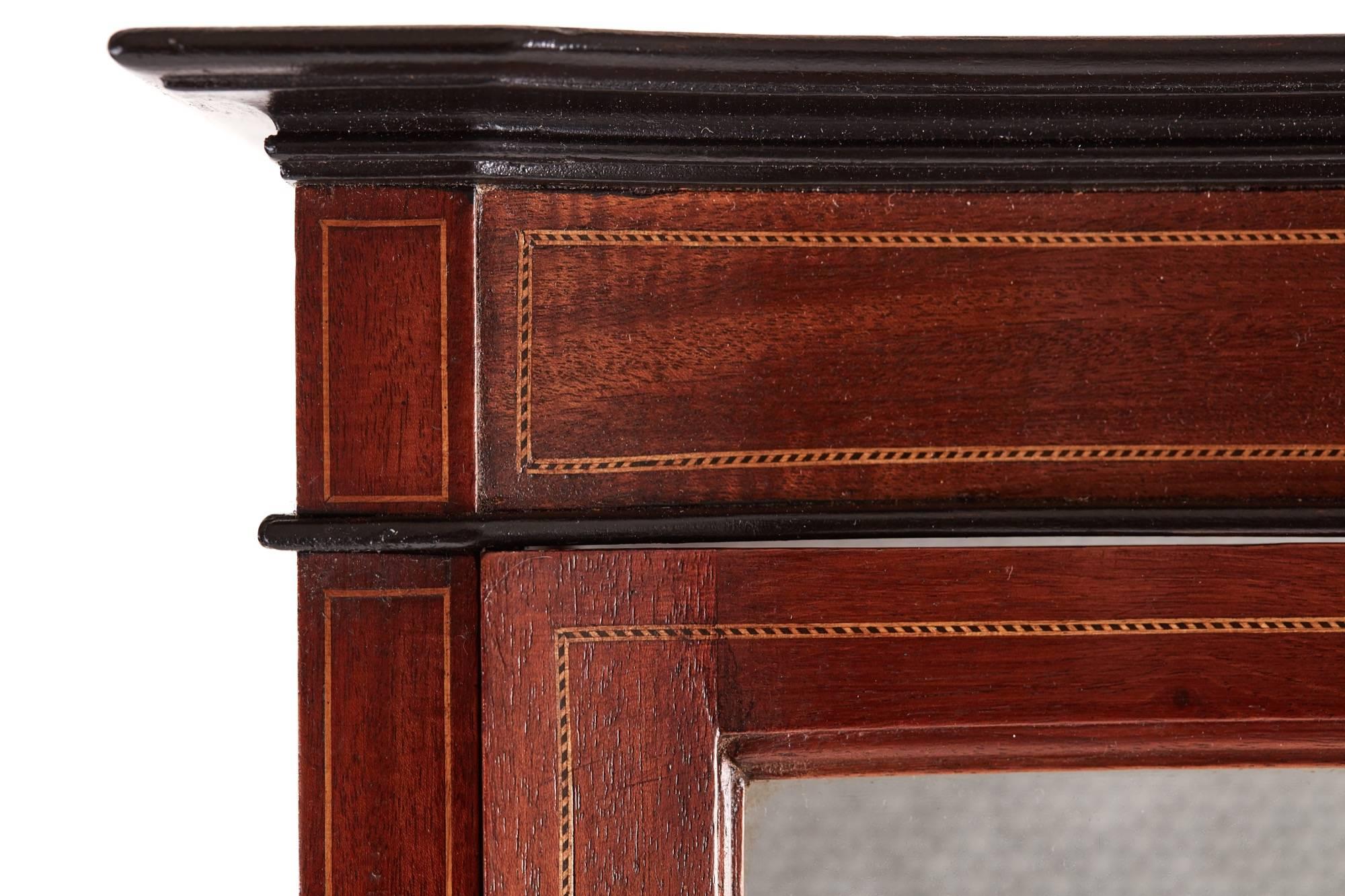 Edwardian inlaid mahogany serpentine front display cabinet, with a inlaid top frieze, serpentine shaped glazed door, two glass display shelves interior, raised on square inlaid tapered legs.