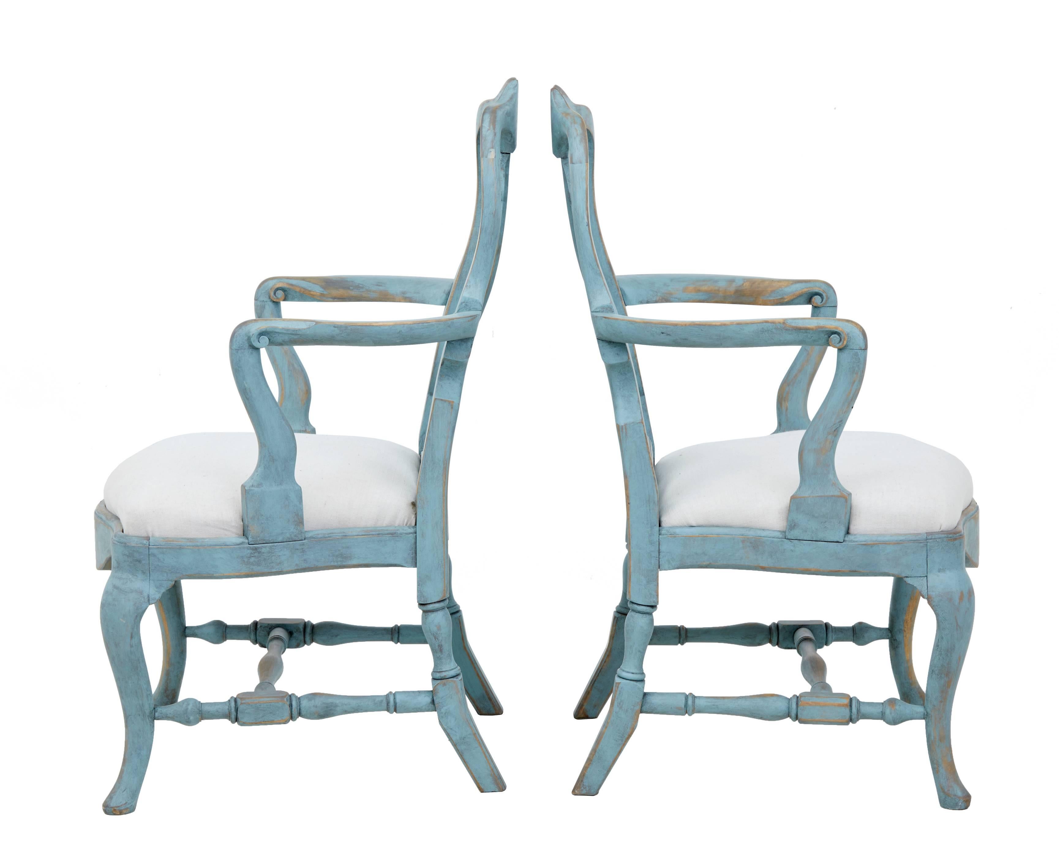 Painted pair of Swedish Gustavian influenced armchairs, circa 1880.
Carved shaped scrolling arms.
Leading down to shaped front with drop in seats.
Later distressed paint.

Measures: Height 38 1/4"
Width 25 1/2"
Depth 23"
Seat