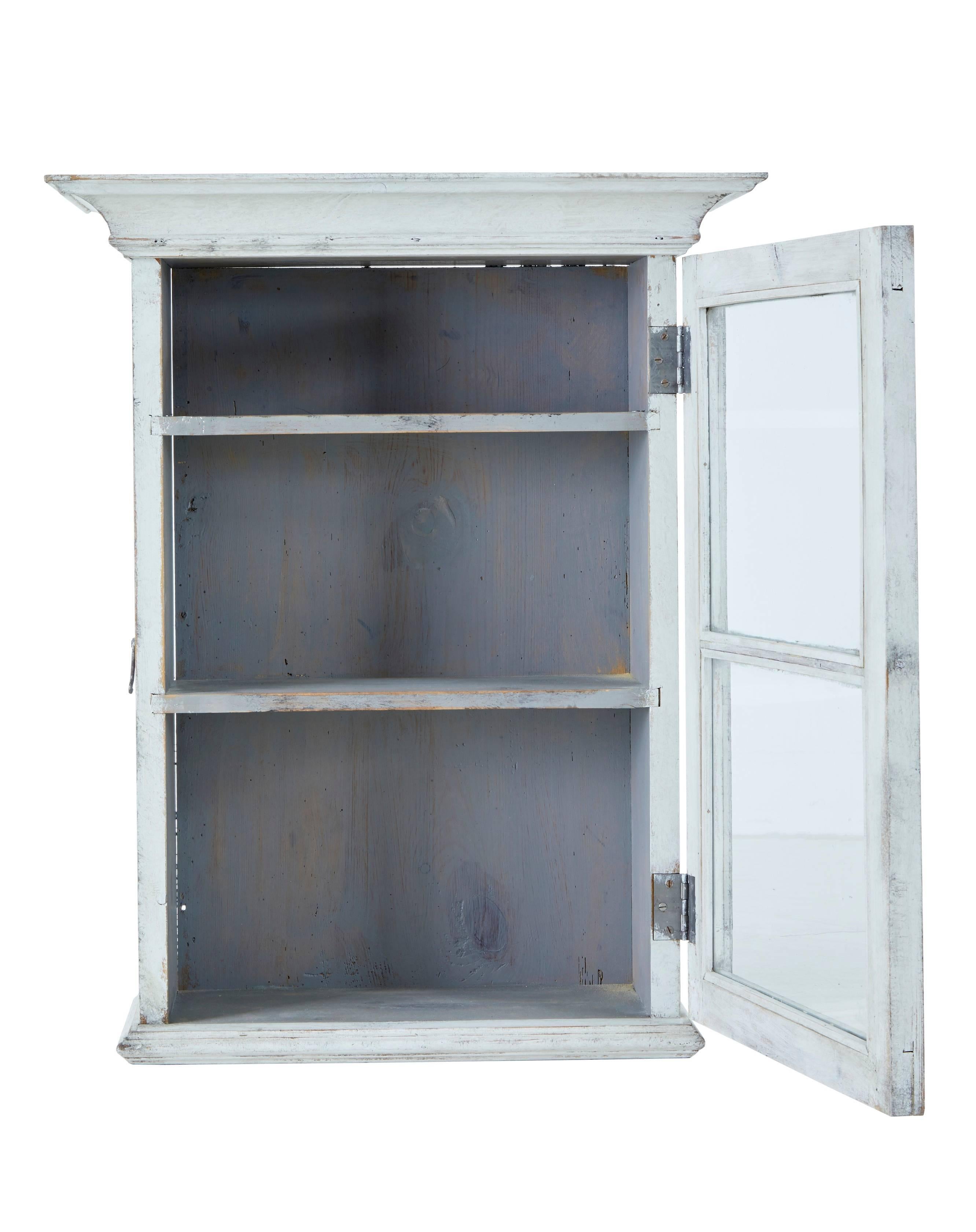 Single door glazed cabinet, circa 1890.
Door with original glazing opens to reveal two shelves. Ideal for the bathroom or hallway.
Later faded and distressed paint.

Measures: Height 30 1/4