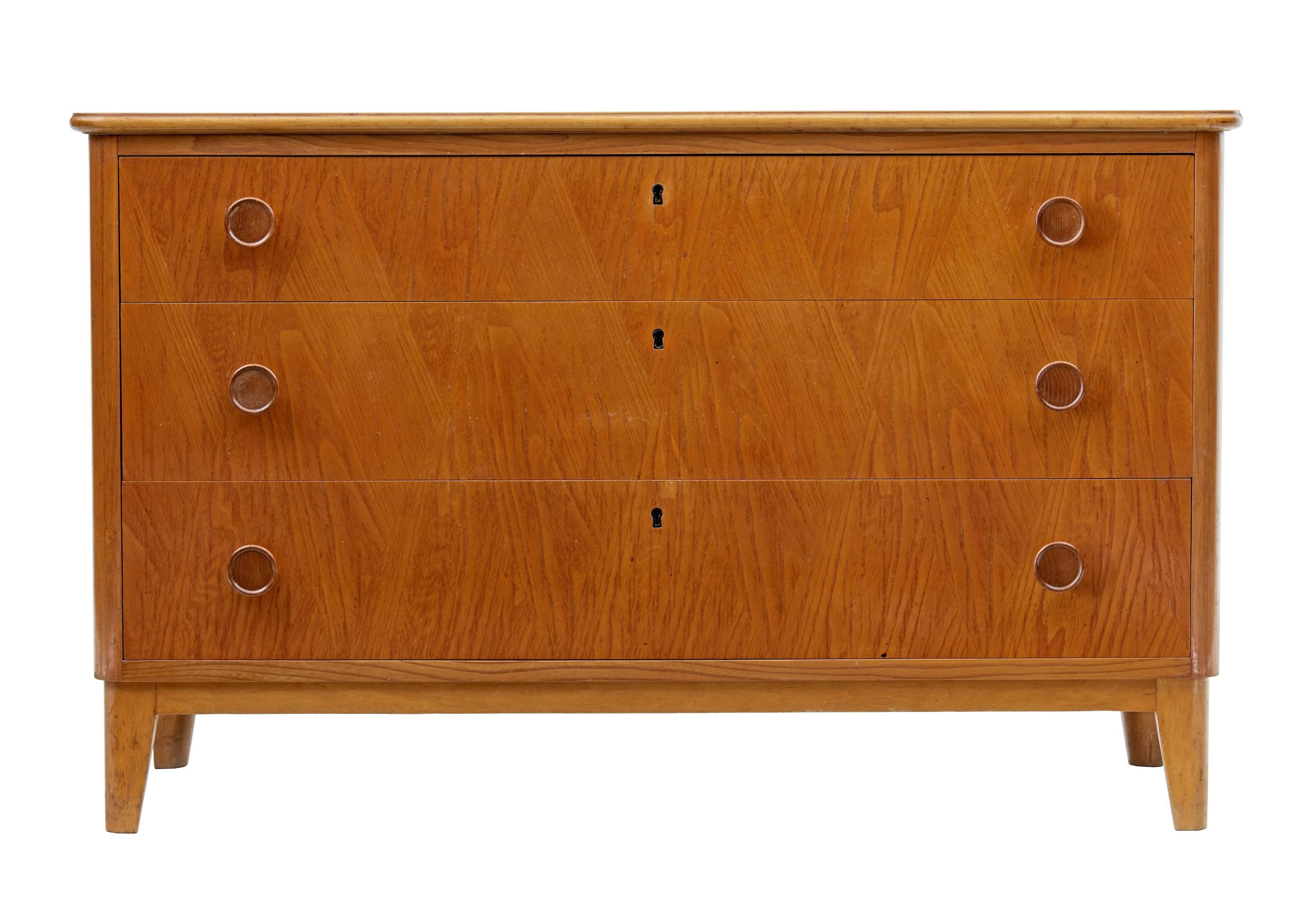 Birch and elm chest of drawers, circa 1950.
Three drawer chest with turned handles.
Birch frame with elm veneered door fronts.
Some surface marks to top.

Measures: Height 25 1/4"
Width 41"
Depth 17 1/4".
  