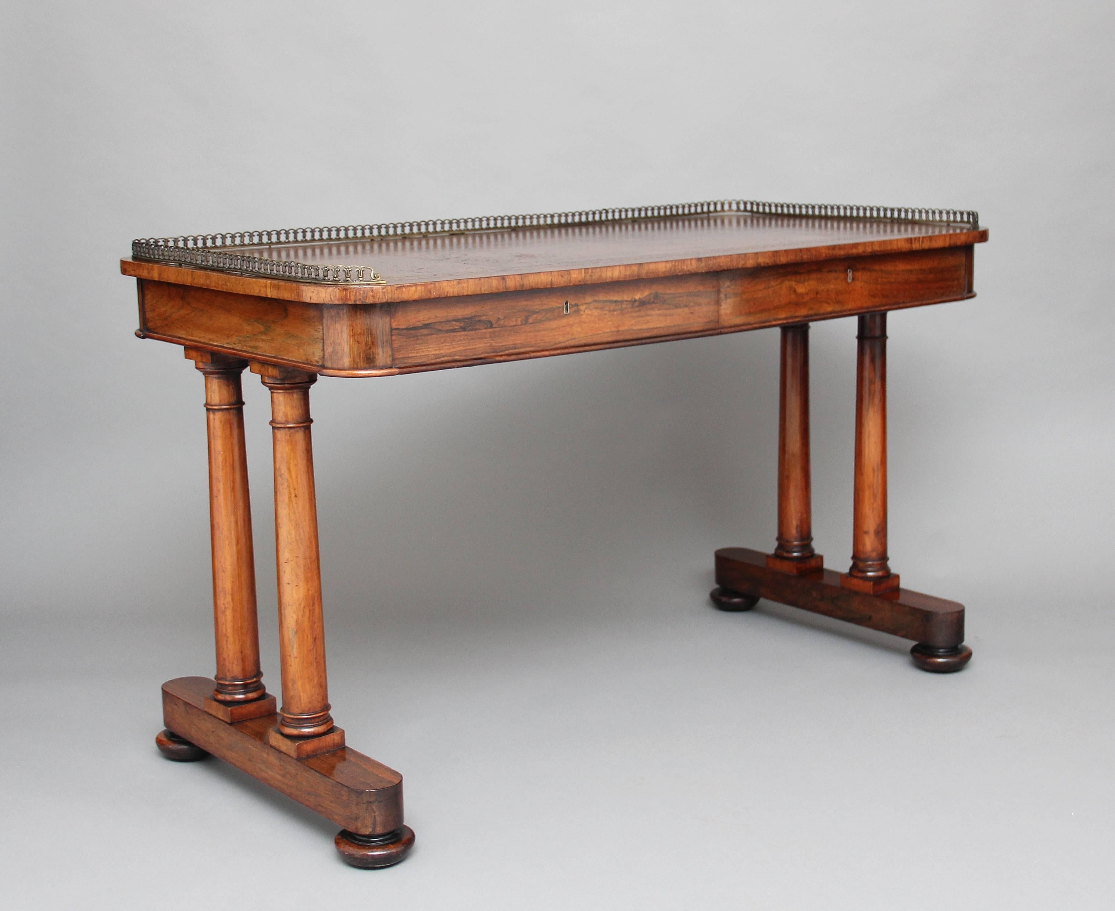 A lovely quality early 19th century rosewood or sofa writing table by “Miles & Edward” the rounded rectangular top with a tan brown leather writing surface with blind and gold tooling, the top having a three quarter brass colonnade gallery, with