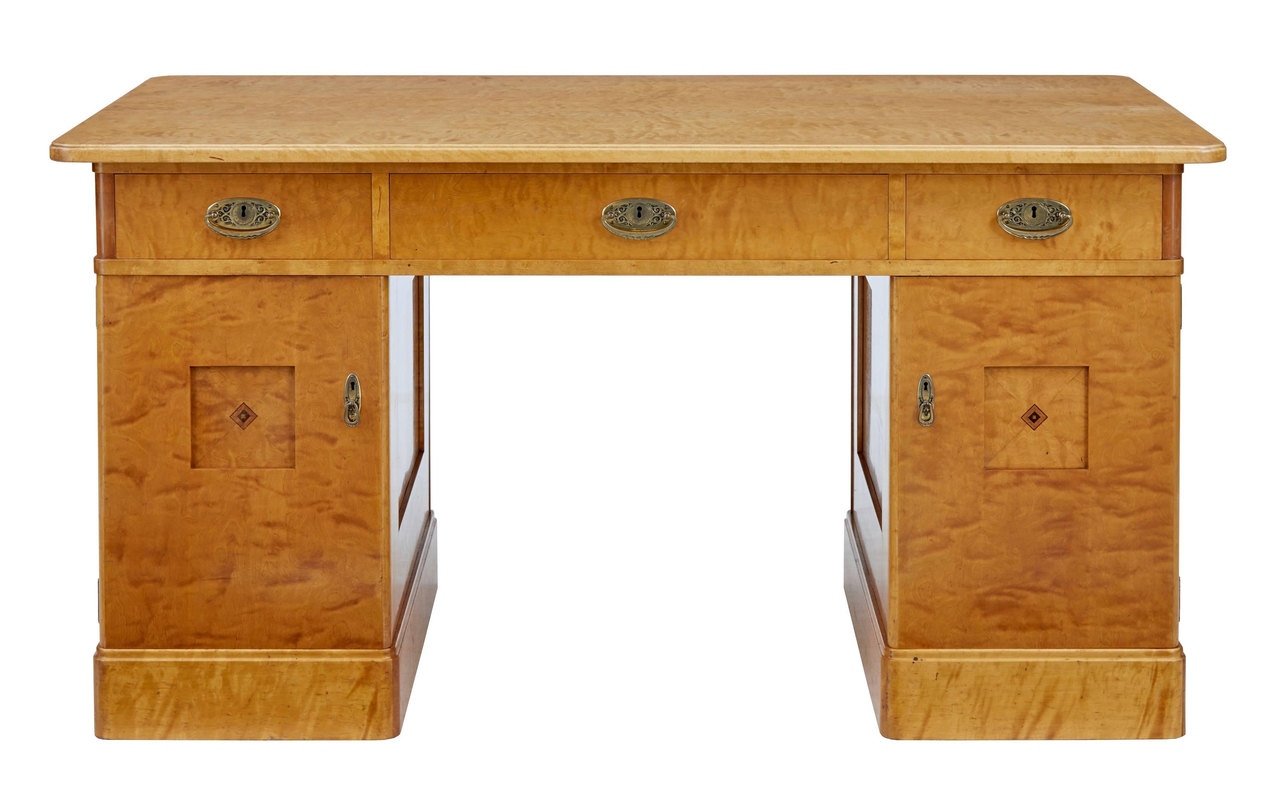 Good quality birch pedestal desk, circa 1895.
Desk comprising of three parts.
Top with flat birch veneered writing surface, below which are three full depth drawers which open with ornate brass handles.
Pedestal doors with small inlaid design to