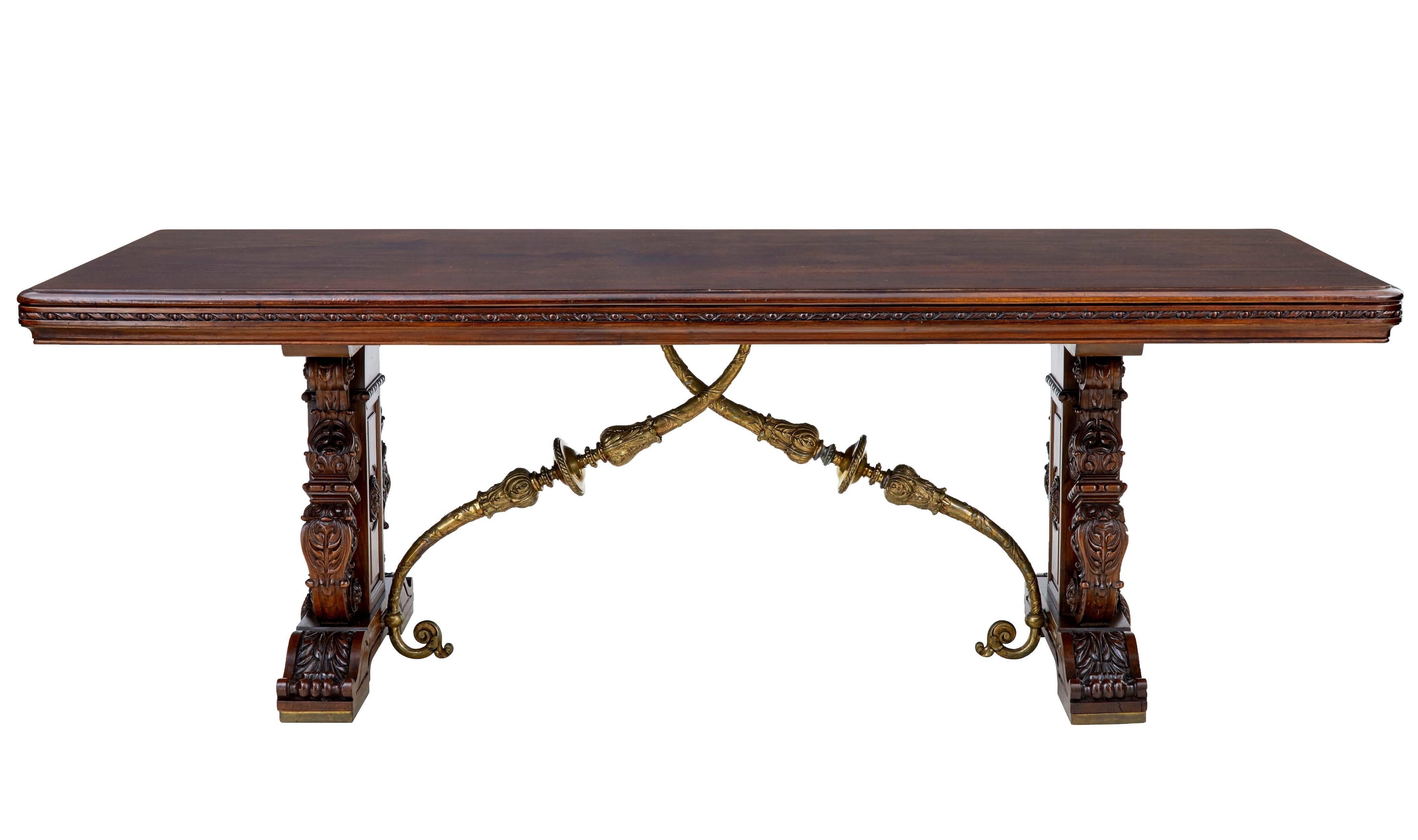 Stunning French walnut dining table, circa 1880.
Rare table, made to showcase continental table design. Italian inspired carved trestle ends with scrolling supports and applied shells. The table gains its Spanish influenced from the bronze cross