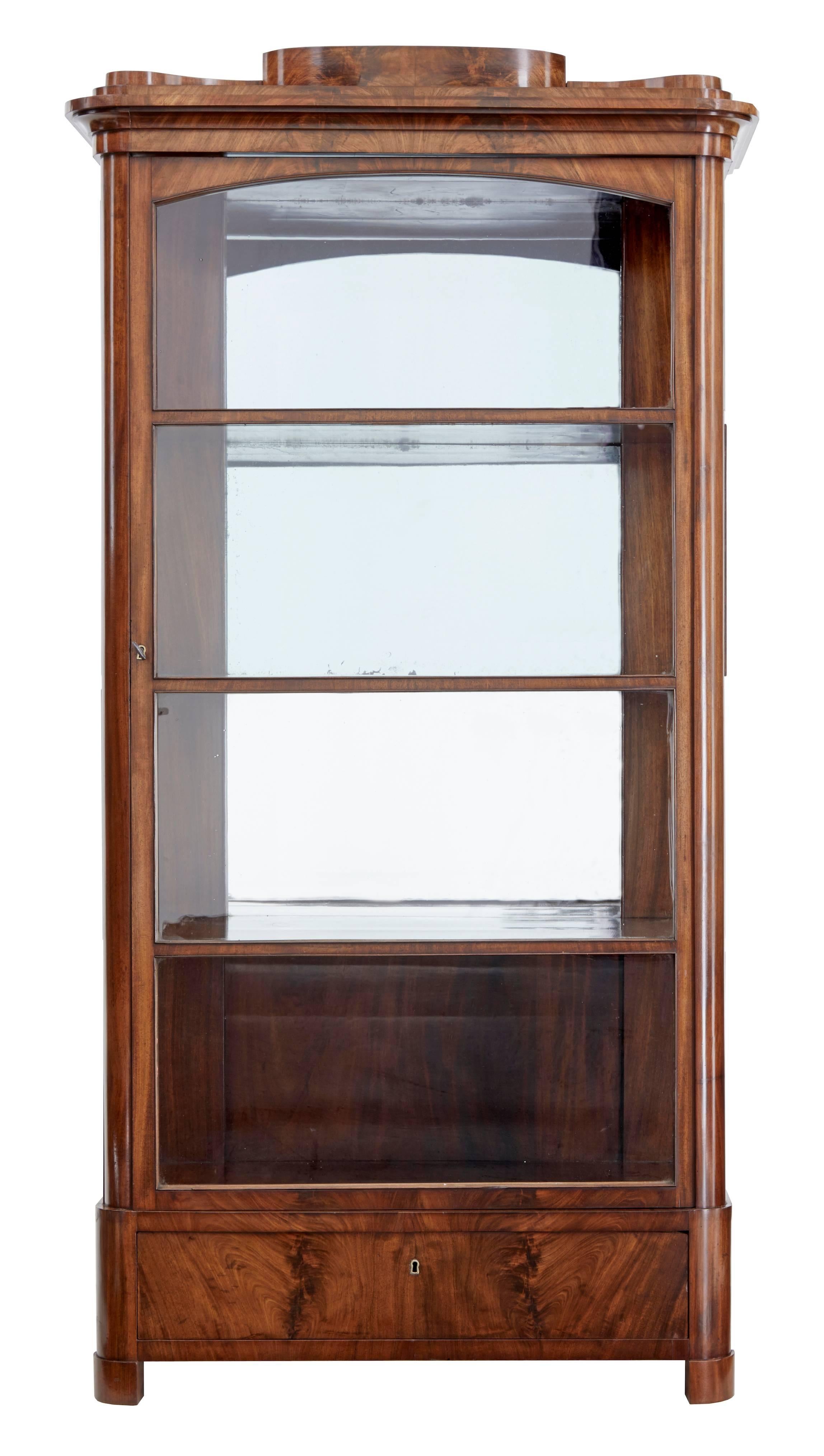 Fine quality Danish display cabinet, circa 1840.
Flame mahogany veneered cabinet with three mahogany shelves behind the single glazed door.
Interior offers four display apertures.
Original mirrored back with minor plate loss.
Single drawer to