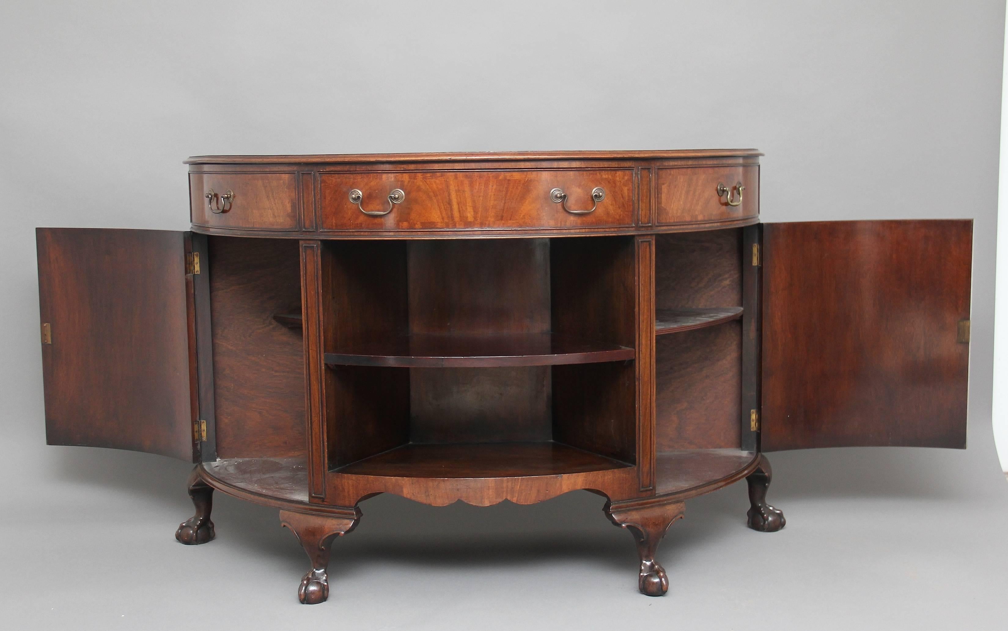 Early 20th century mahogany demilune cabinet, the semi-circular moulded edge top above a fitted frieze drawer at the centre flanked either side with two faux drawers fitted with brass swan neck handles, with an open cabinet at the centre with a