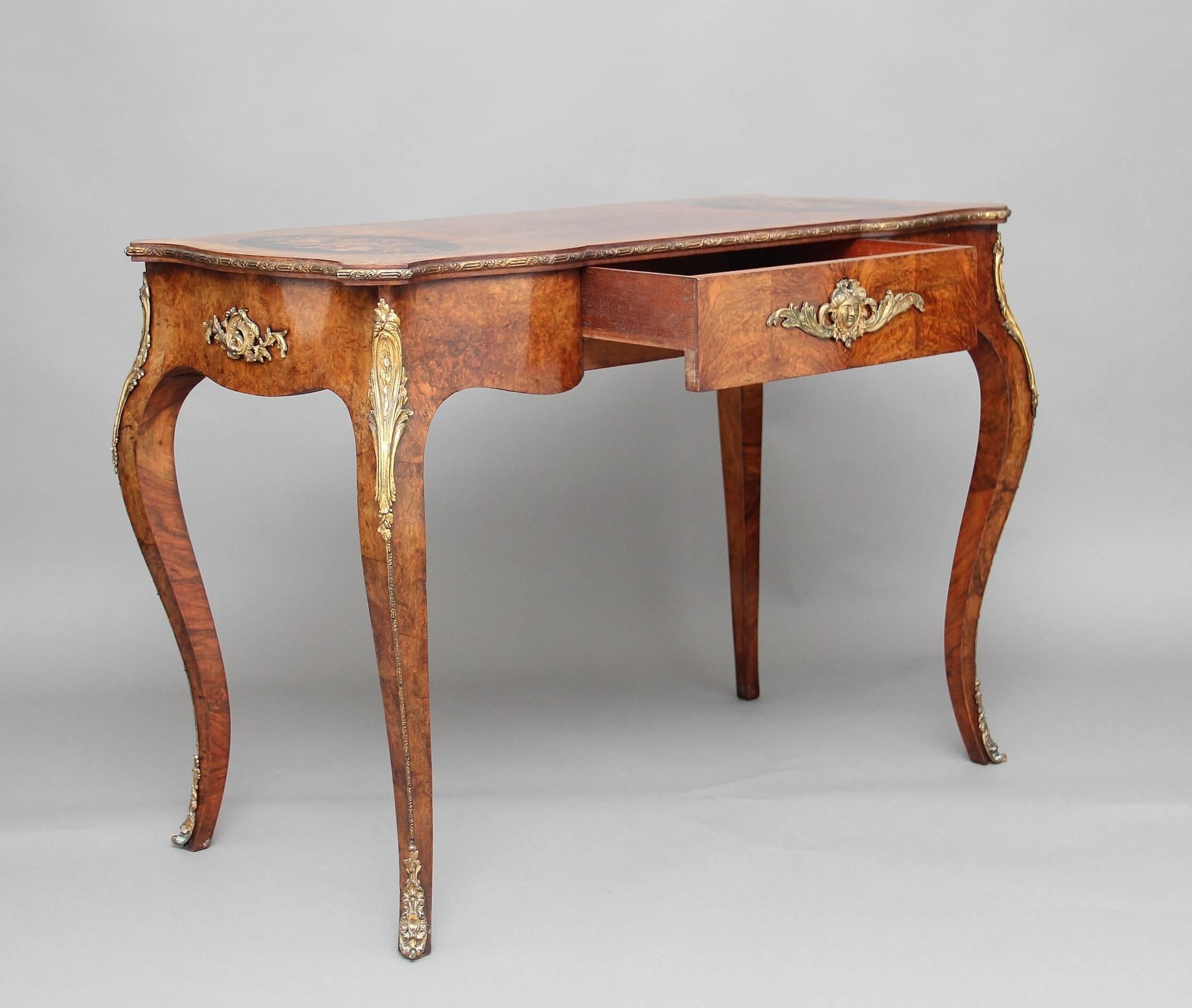 19th century walnut and ormolu-mounted writing table of serpentine form, the shaped top crossbanded in kingwood, with floral inlaid oval panels with an ebonized background, with a shaped frieze below running along the front, sides and back, which