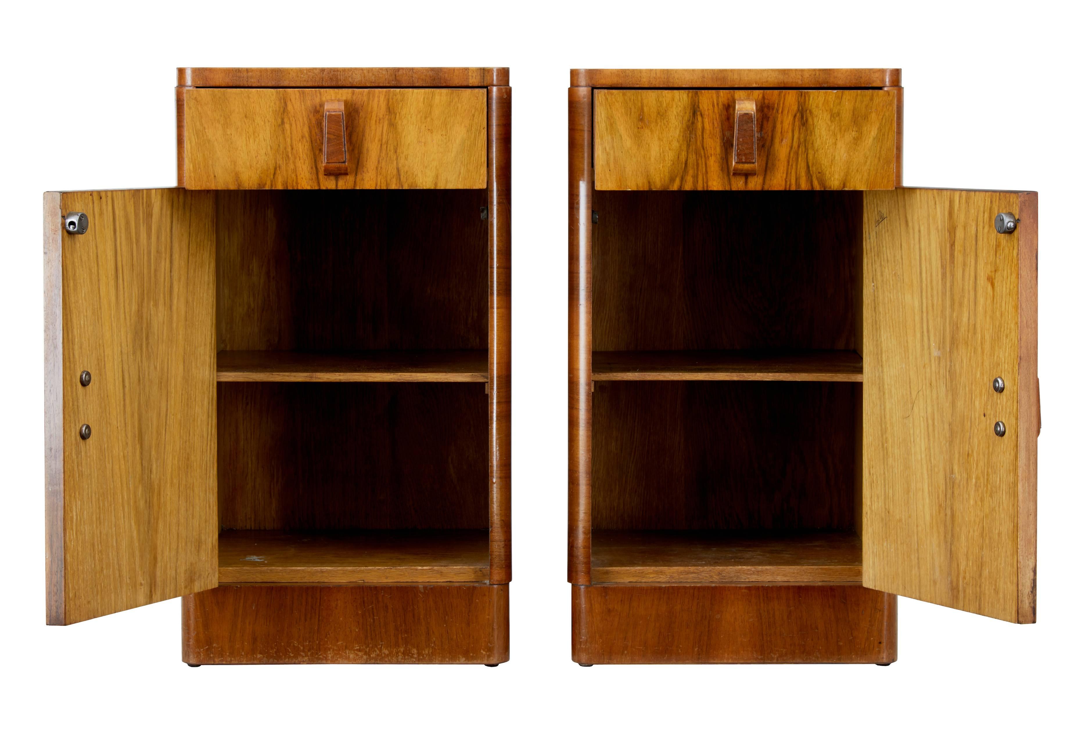 Elegant pair of Art Deco bedside cupboards.
Beautiful figured walnut veneers with quarter veneer top creating a stunning pattern to the top.
Single drawer with single door below containing a single shelf.
Standing on brass studs.
Minor surface