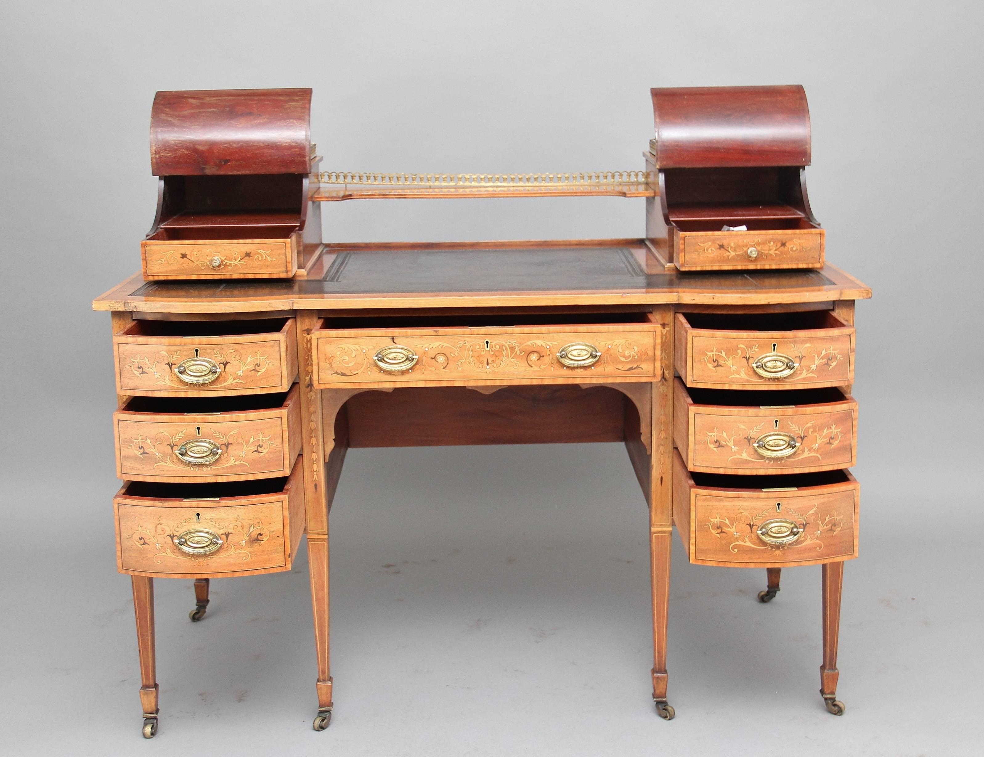 Early 20th Century mahogany inlaid desk, the top having a shelf flanked either side by concave hinged stationary compartments beautifully inlaid with scrolling flowers and urns, each with a drawer, one fitted with a pair of inkwells, the other with