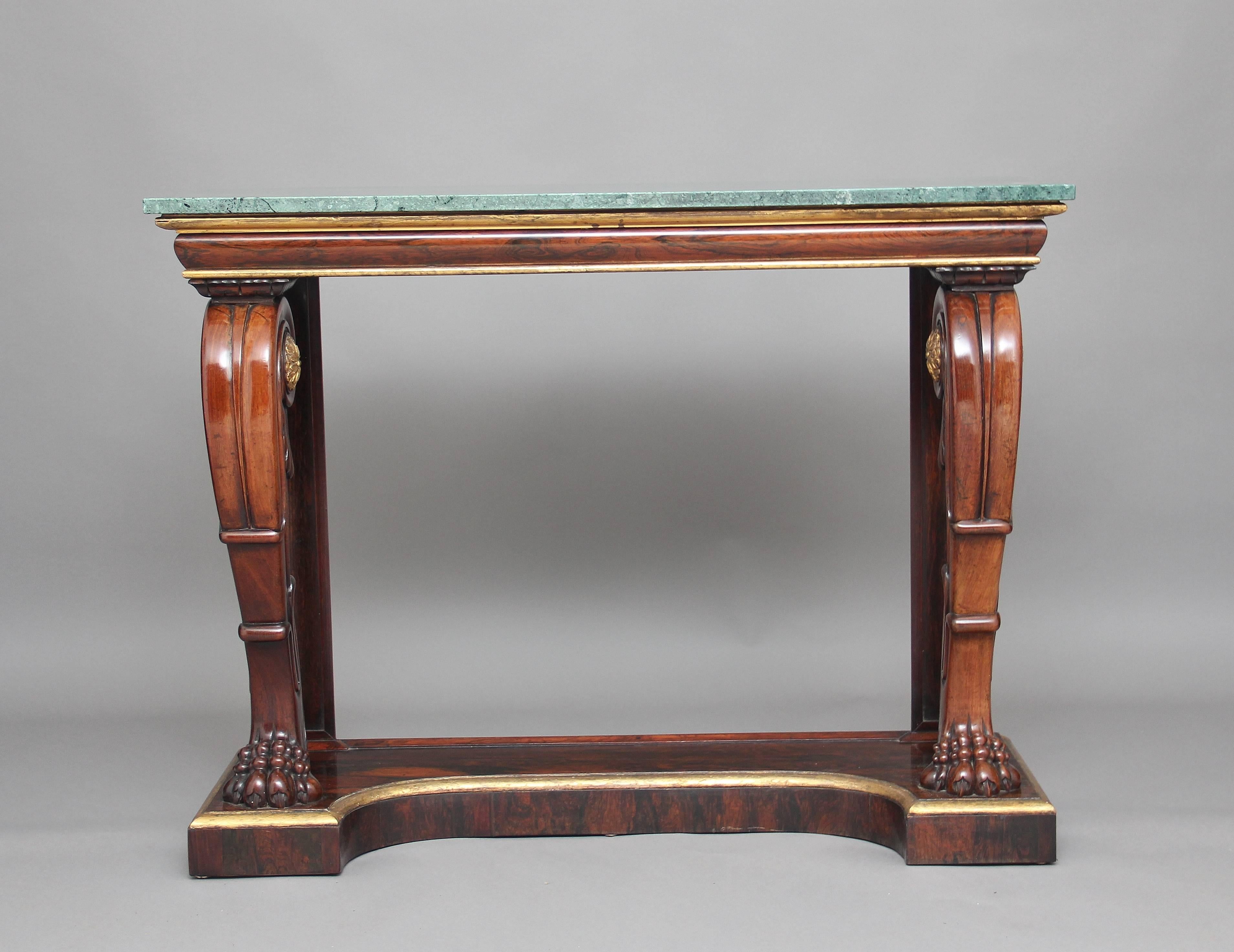 Early 19th century rosewood console table with a turquoise marble top, the frieze below having a gilt moulded edge, supported on carved bold cabriole front supports with claw feet decorated with carved giltwood patraes, standing on a gilded and