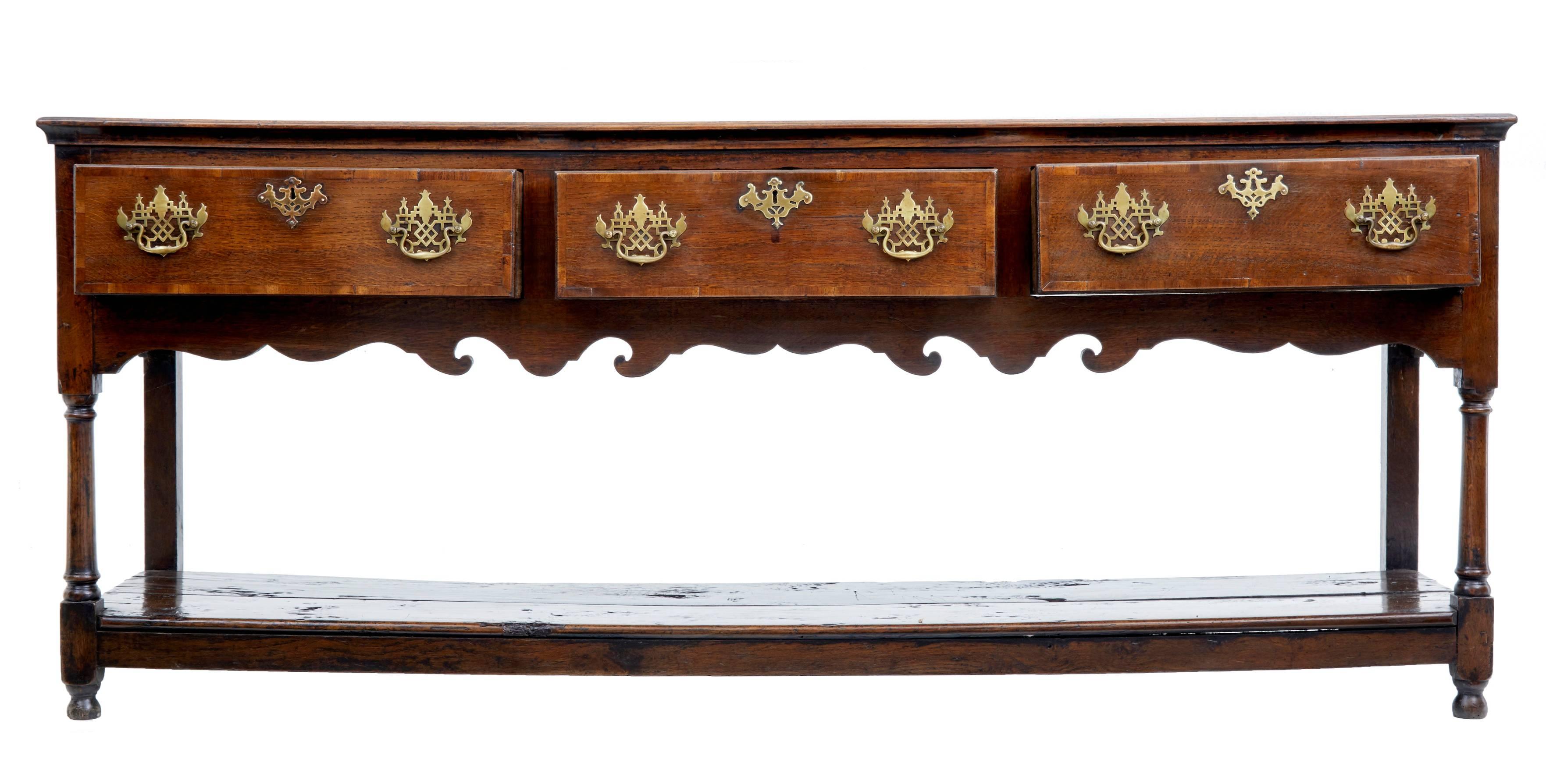 A very pretty 18th century oak dresser base, circa 1750.
Crossbanded with mahogany on the top and drawer fronts.
Pierced brass handles.
Standing on turned front legs, supporting a two plank pot board shelf.
Very good color and