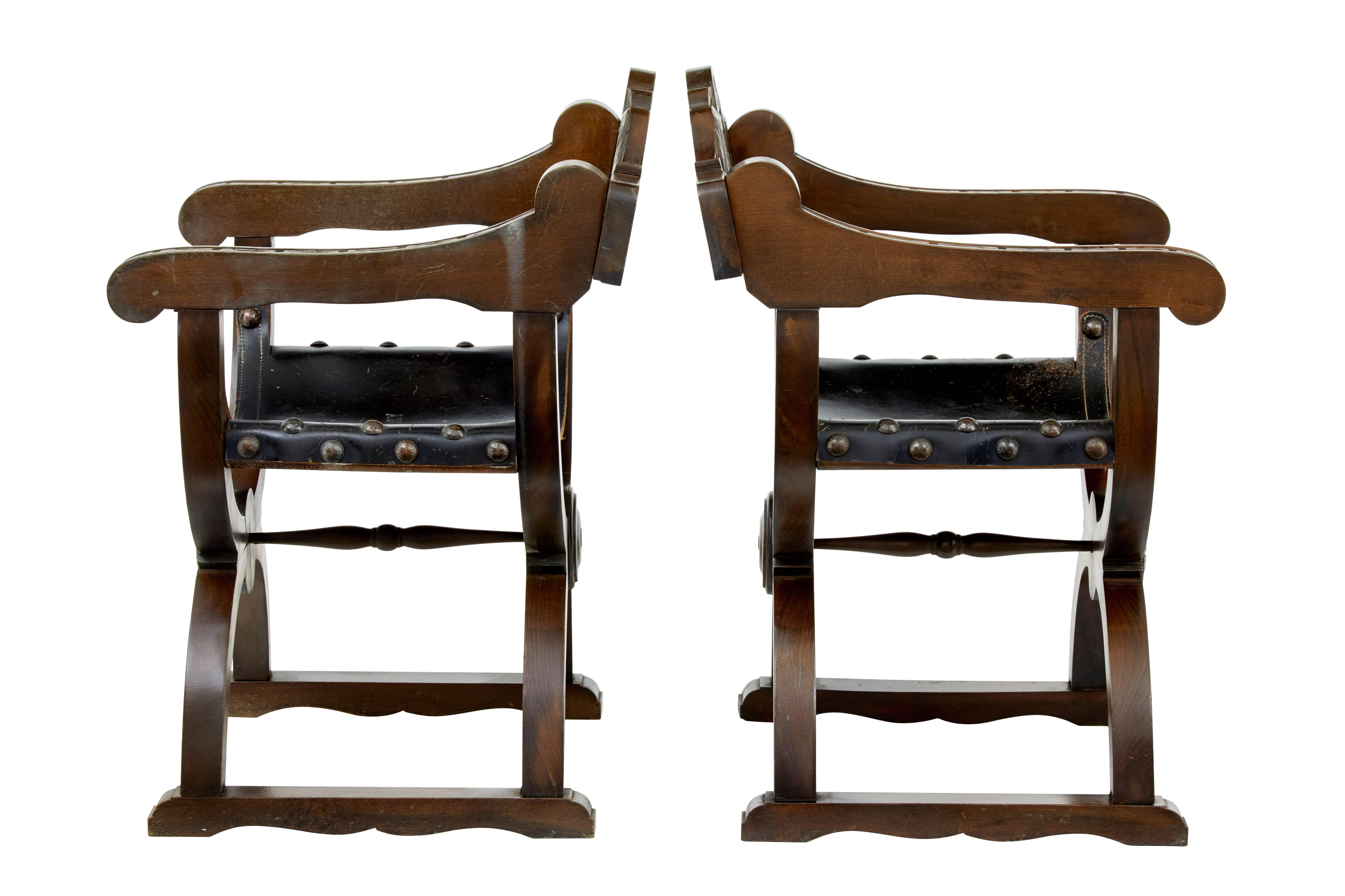 Pair of decorative carved oak Dante / Savonarola X-frame chairs circa 1900.
Carved back with stylized coat of arms.
X-frame legs, standing on sledge feet.
Leather seat in good order.

Measures: Height 31