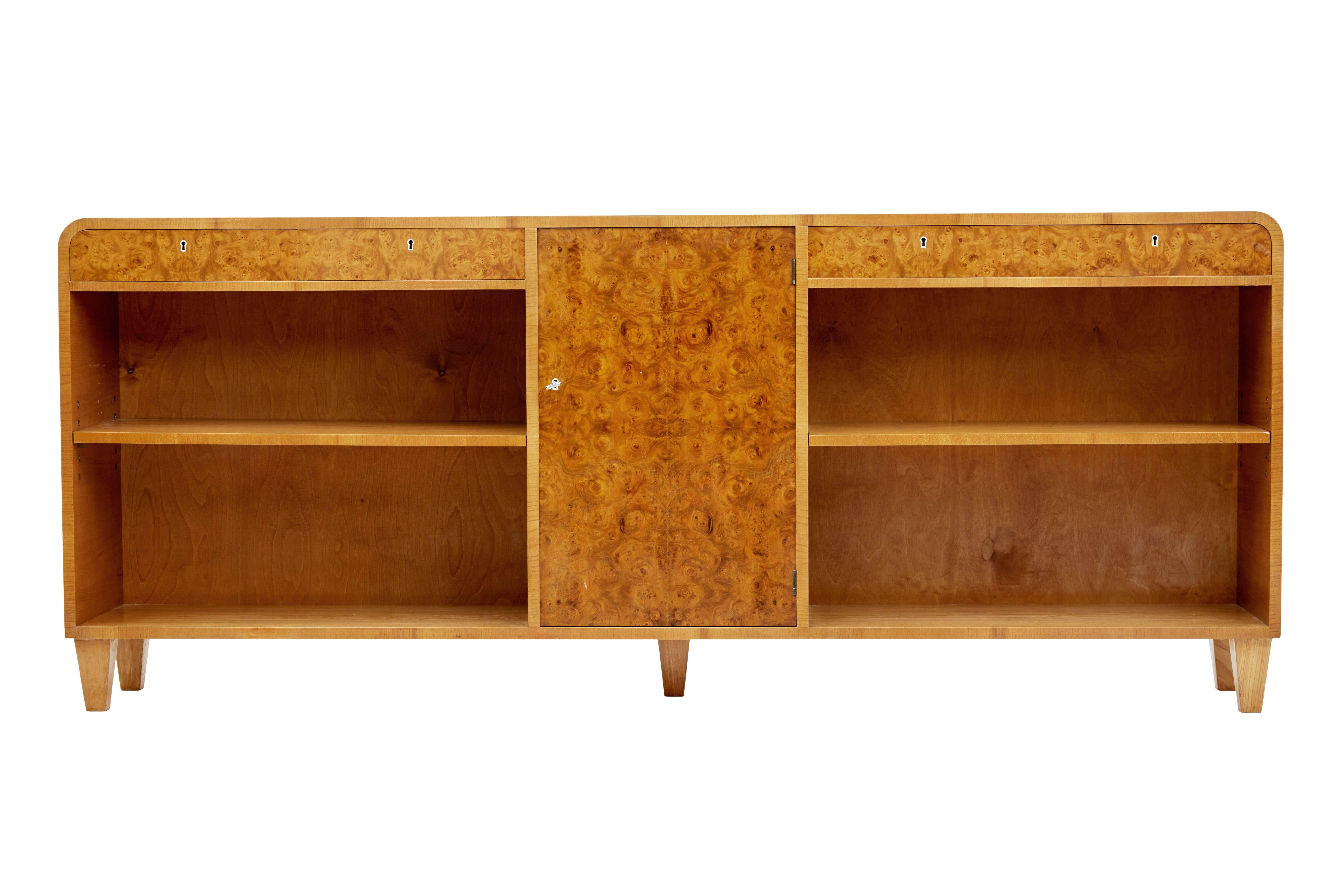 Good quality low bookcase by Peterson & Nilson of Stockholm, circa 1950.

Flowing shape to this fabulous piece of Scandinavian design. Central cupboard containing two shelves is flanked either side by a single shelf bookcase above which are two