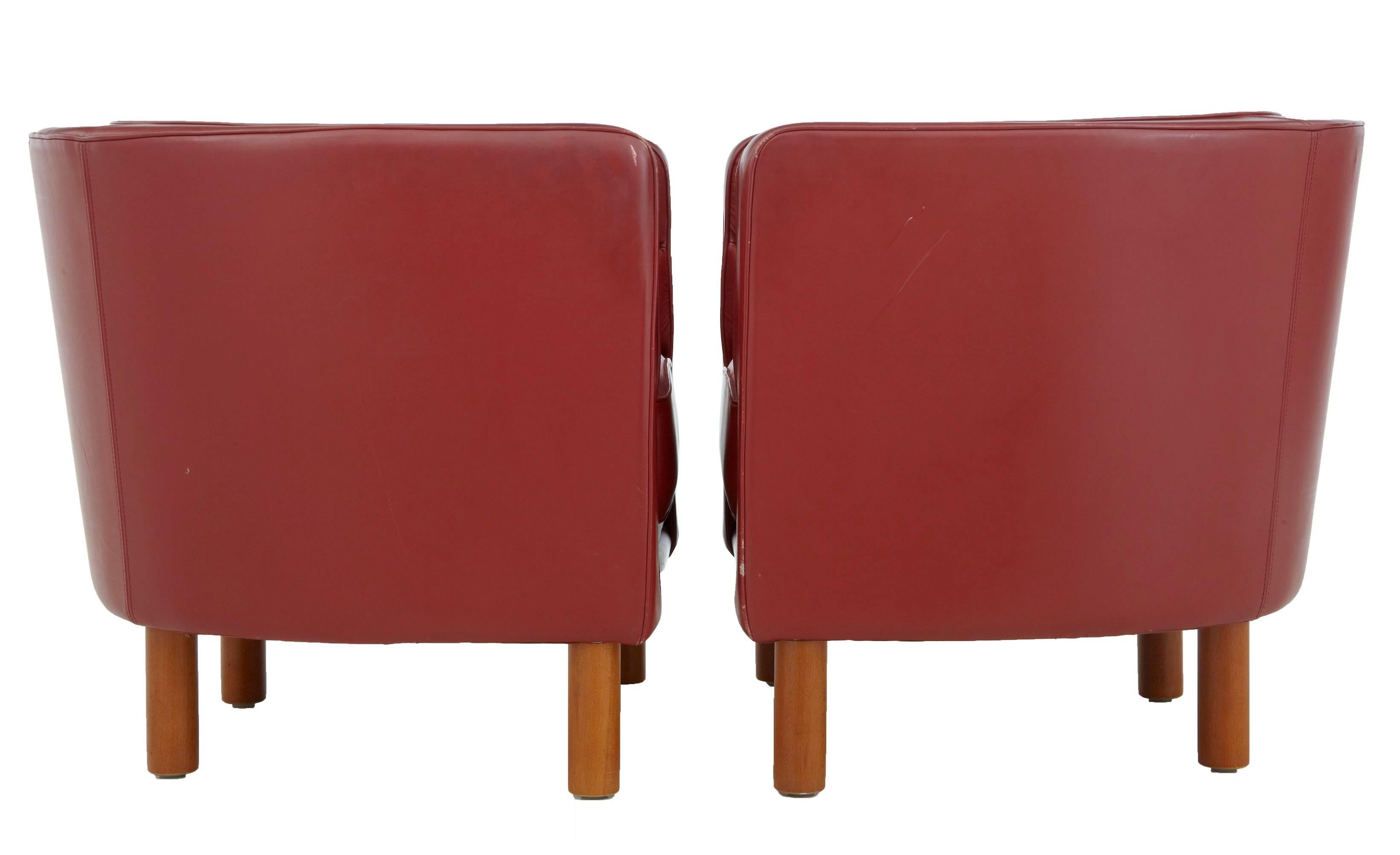 Upholstered in rusty red leather. Beech round legs and exposed front under frame. Very comfortable and stylish. Some minor wear to leather piping, odd mark to leather around the outside, minor scuff marks to wood frame. We have four pairs of these