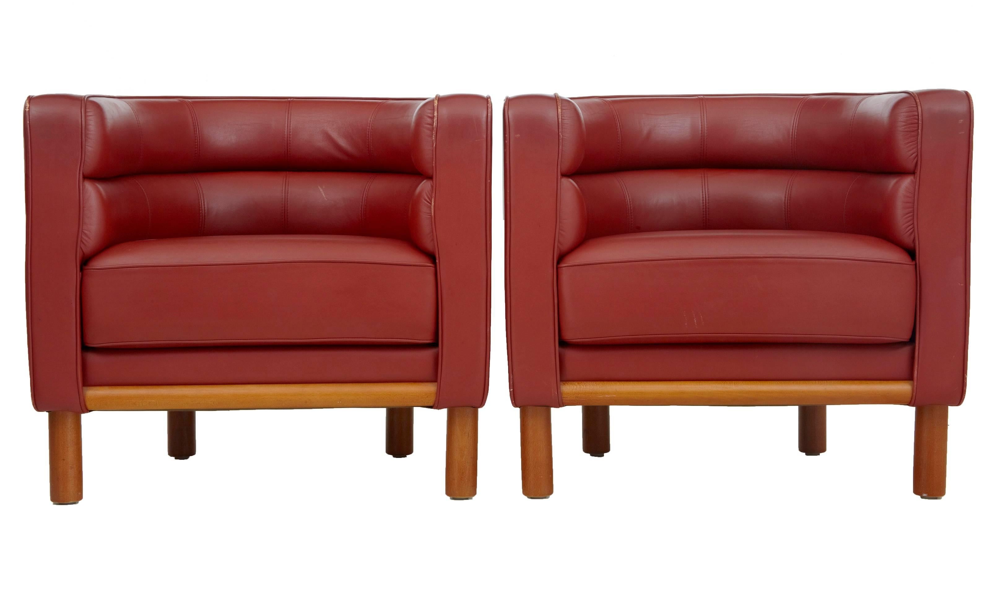 Upholstered in rusty red leather. Beech round legs and exposed front under frame. Very comfortable and stylish. Some minor wear to leather piping, odd mark to leather around the outside, minor scuff marks to wood frame we have four pairs of these