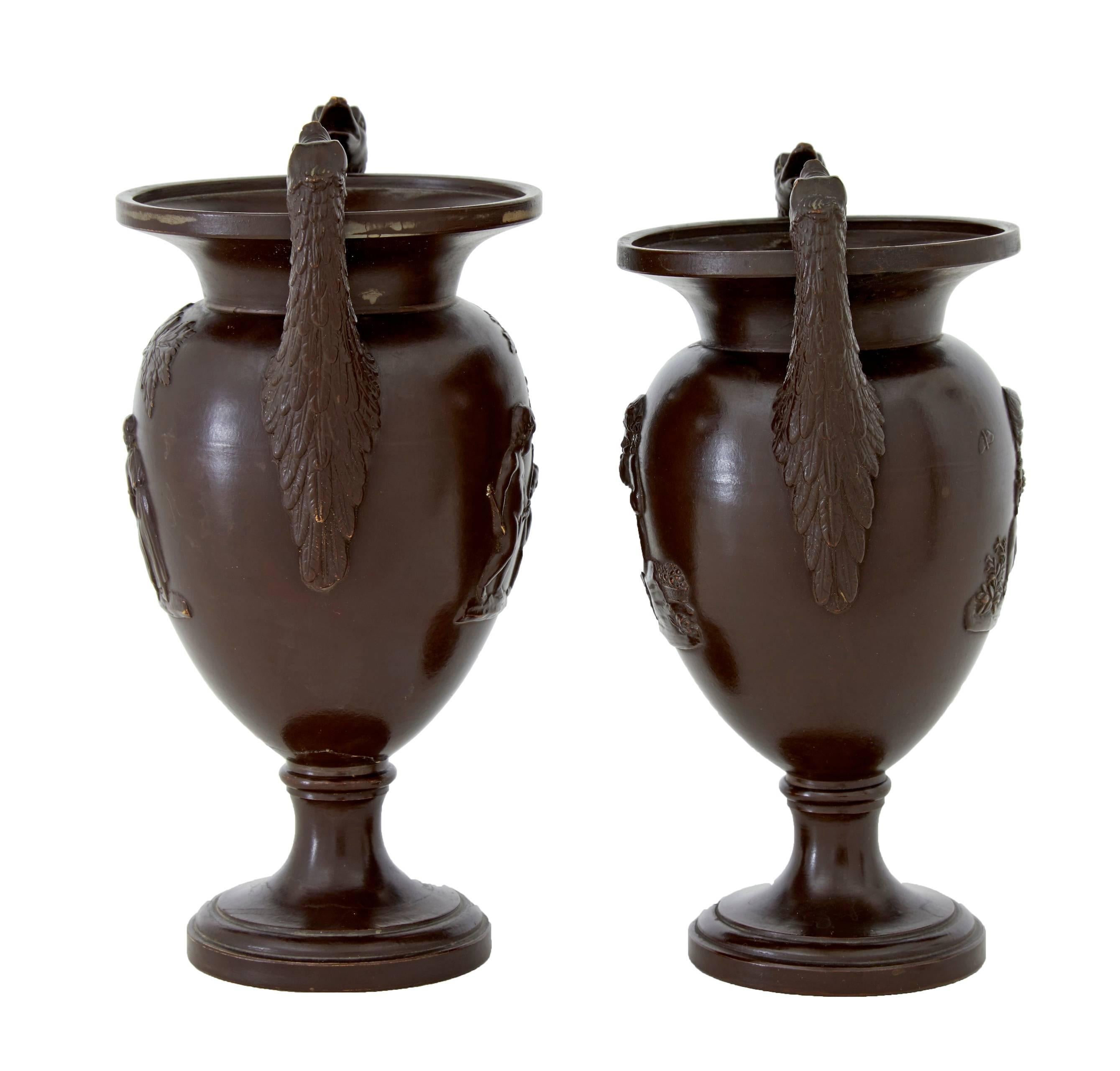 A near pair of urn vases stamped underneath s&g, circa 1930. Applied long necked bird handles, decorated with child scenes. Glazed to look like bronze. Repair to one lip and a repair with minor losses to the stem, (photographed).

Measures: Height