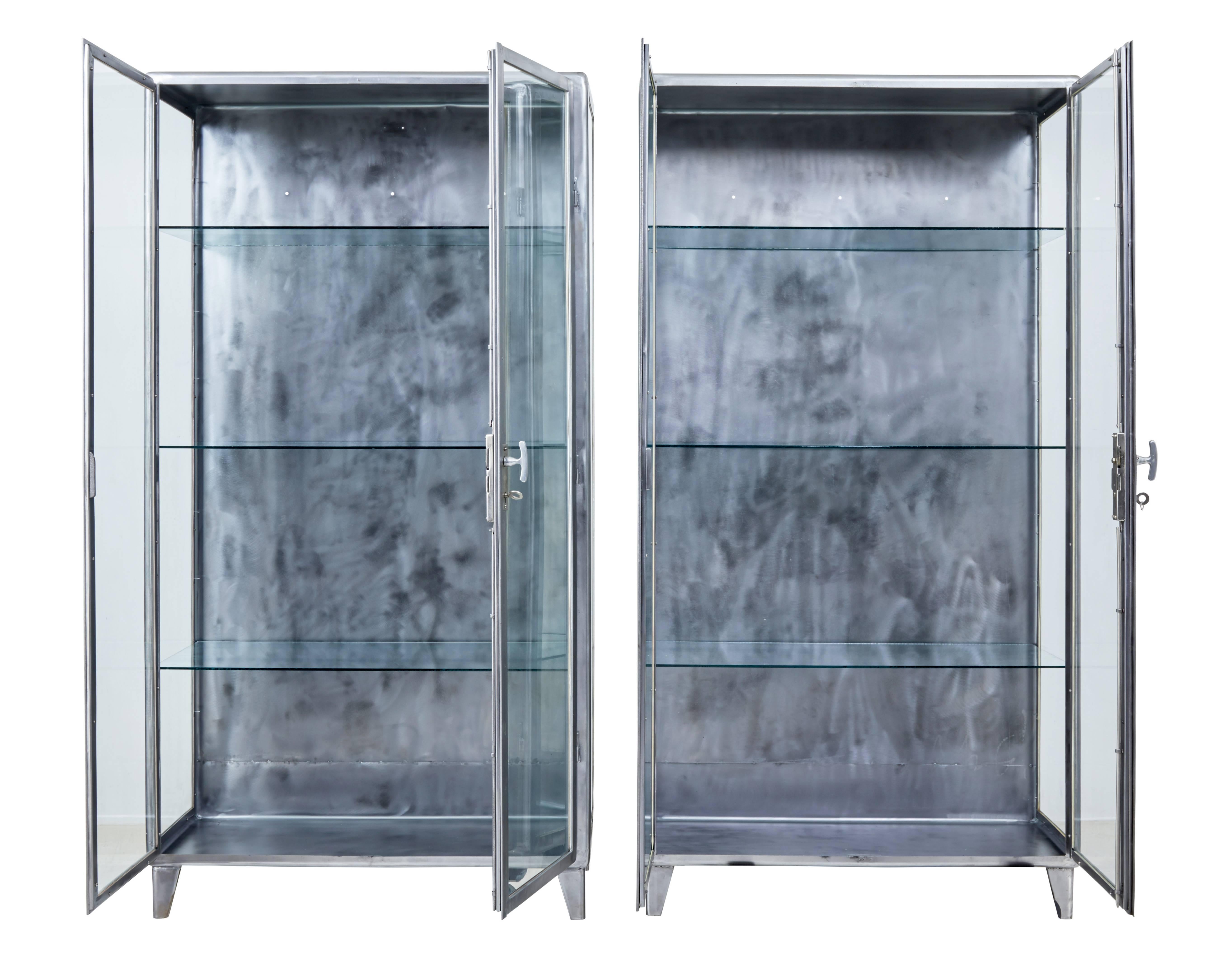 Fine pair of 1920s Art Deco design display cabinets.

These would have been a pair of medical display cabinets that have had the steel polished.

Original locks and keys. Double doors open to reveal 3 glass shelves in each.

Holes in the back