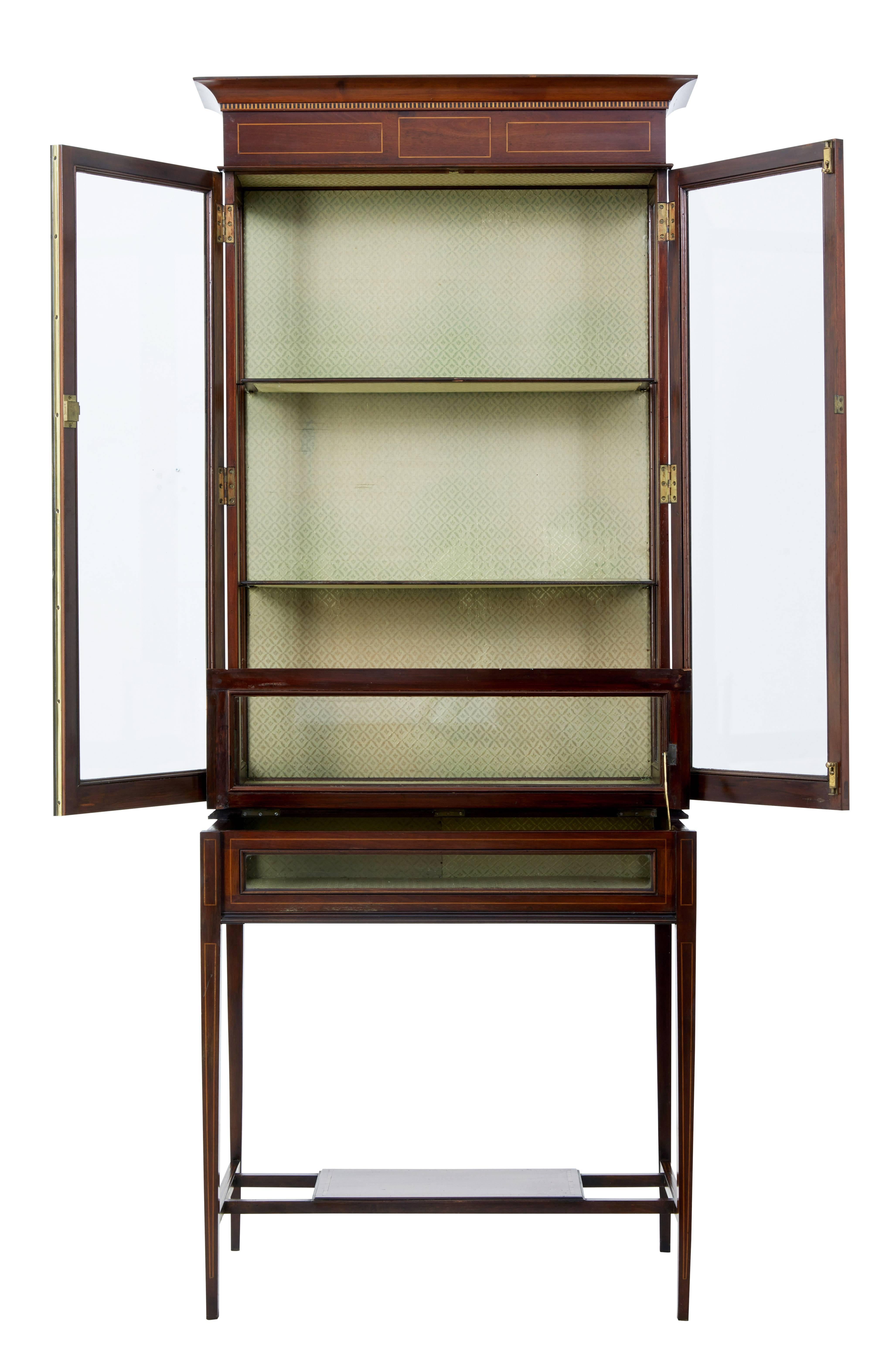 Elegant mahogany display cabinet, circa 1900.

Cross banded and strung in satinwood.

Comprising of two parts, the top section with cornice and dentil frieze detail, double glazed doors open to two fixed position shelves.

Bottom section with