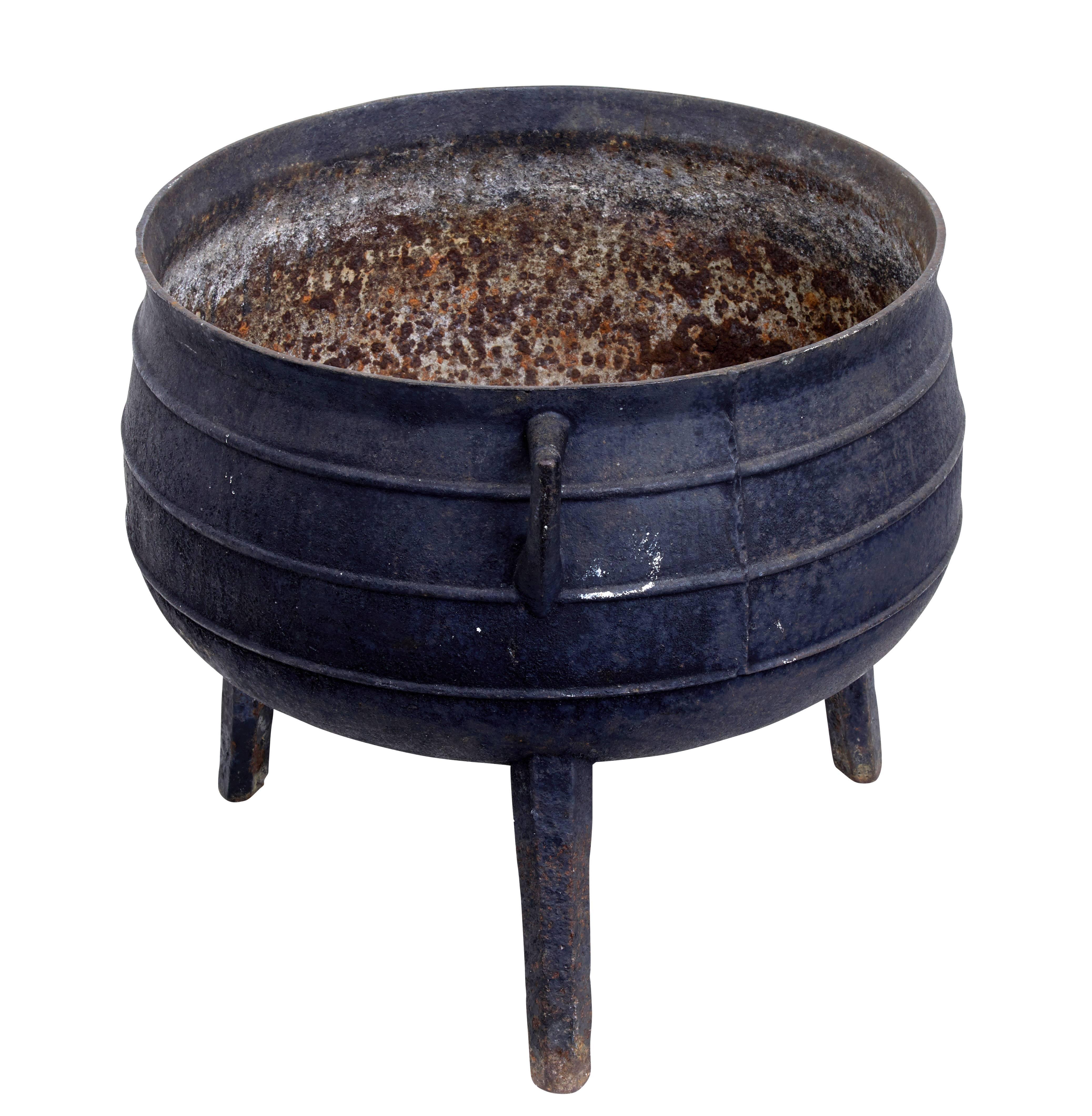 Large 19th century cast iron pot, circa 1890.

This would have been used as a cooking vessel similar to a famine pot.

Ribbed around the outer edge, painted black on the outside. Standing on three legs with two cast handles.

Rust to the