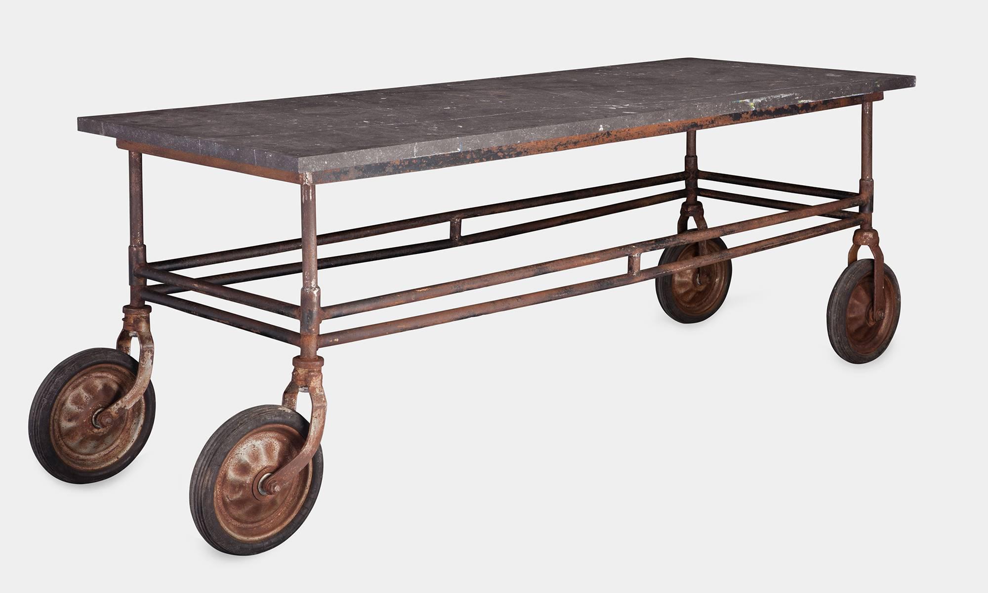 Stone top and iron factory table, circa 1920.

Blue stone slab top on iron base with wheels.