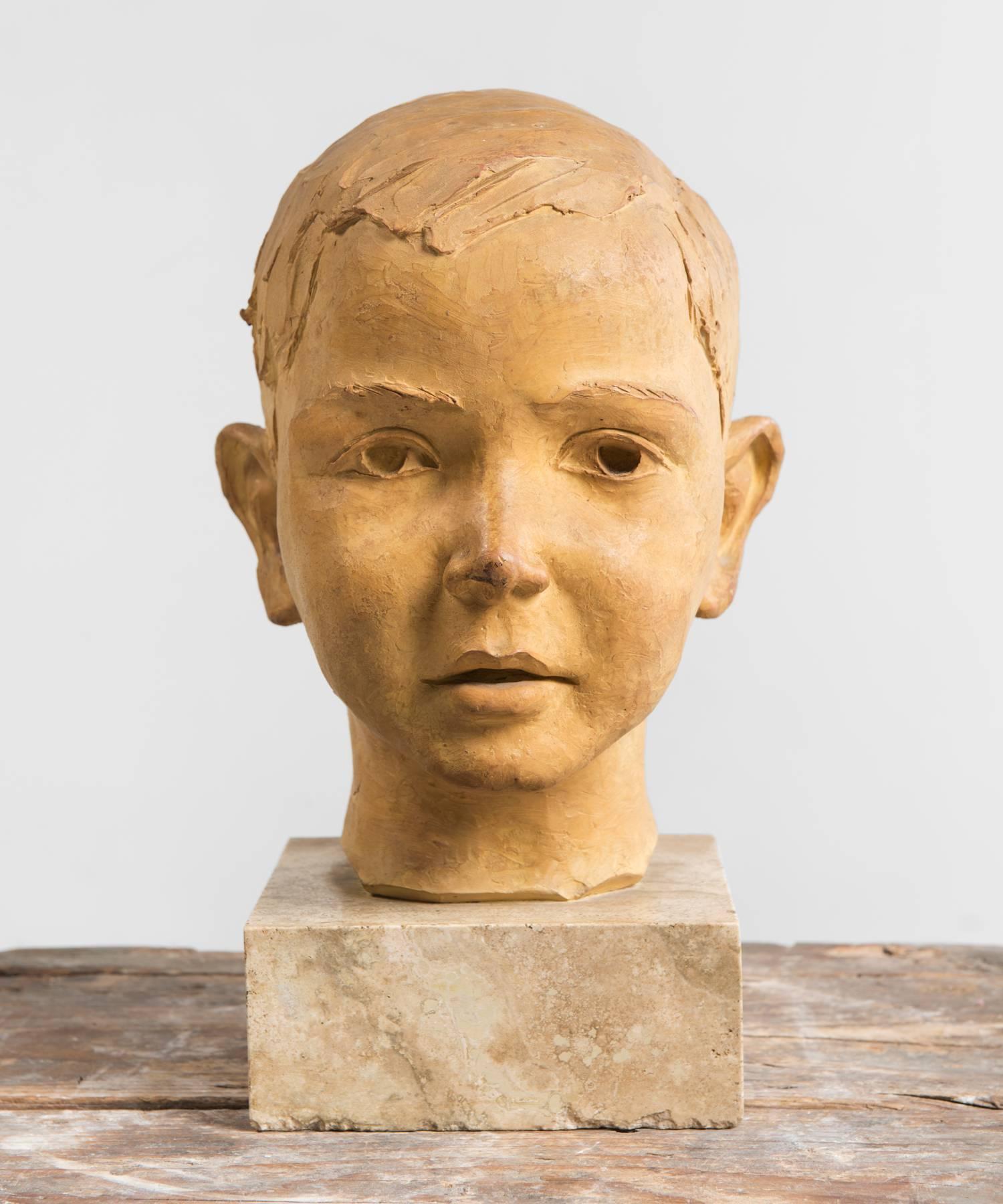 Terracotta bust of a youth, made in Italy, circa 1950.

Sculpture of a boy's head on stone pedestal with artist's signature.