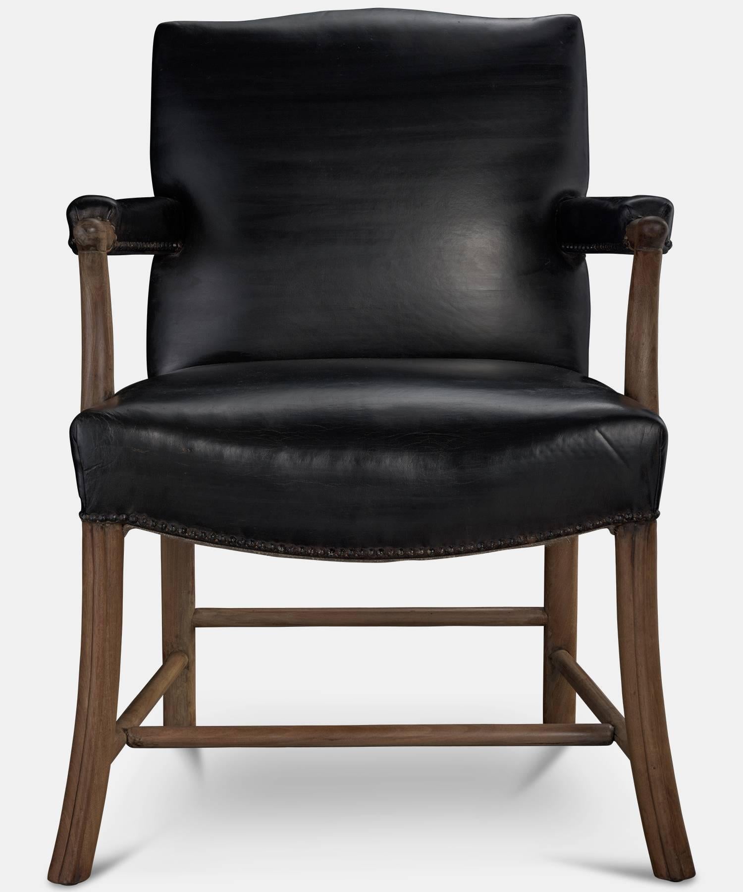 Leather and oak armchair, circa 1950.

Original thick black leather upholstery, with carved wooden frame.