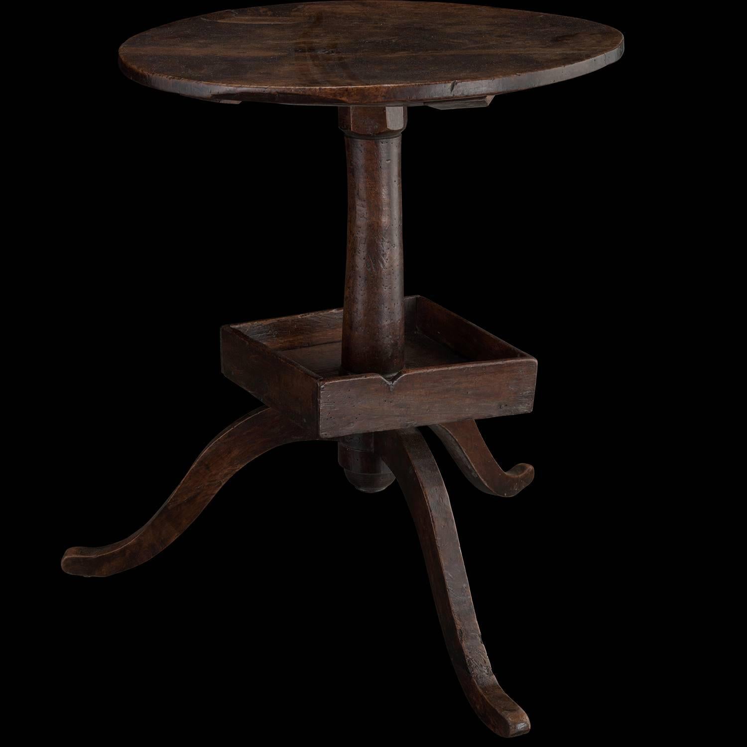 Walnut side table.

France, circa 1760.

Thoughtfully designed, primitively carved table with square inset shelf just above the three splayed legs.

Measures: 20.75" diameter x 25.5" height.
