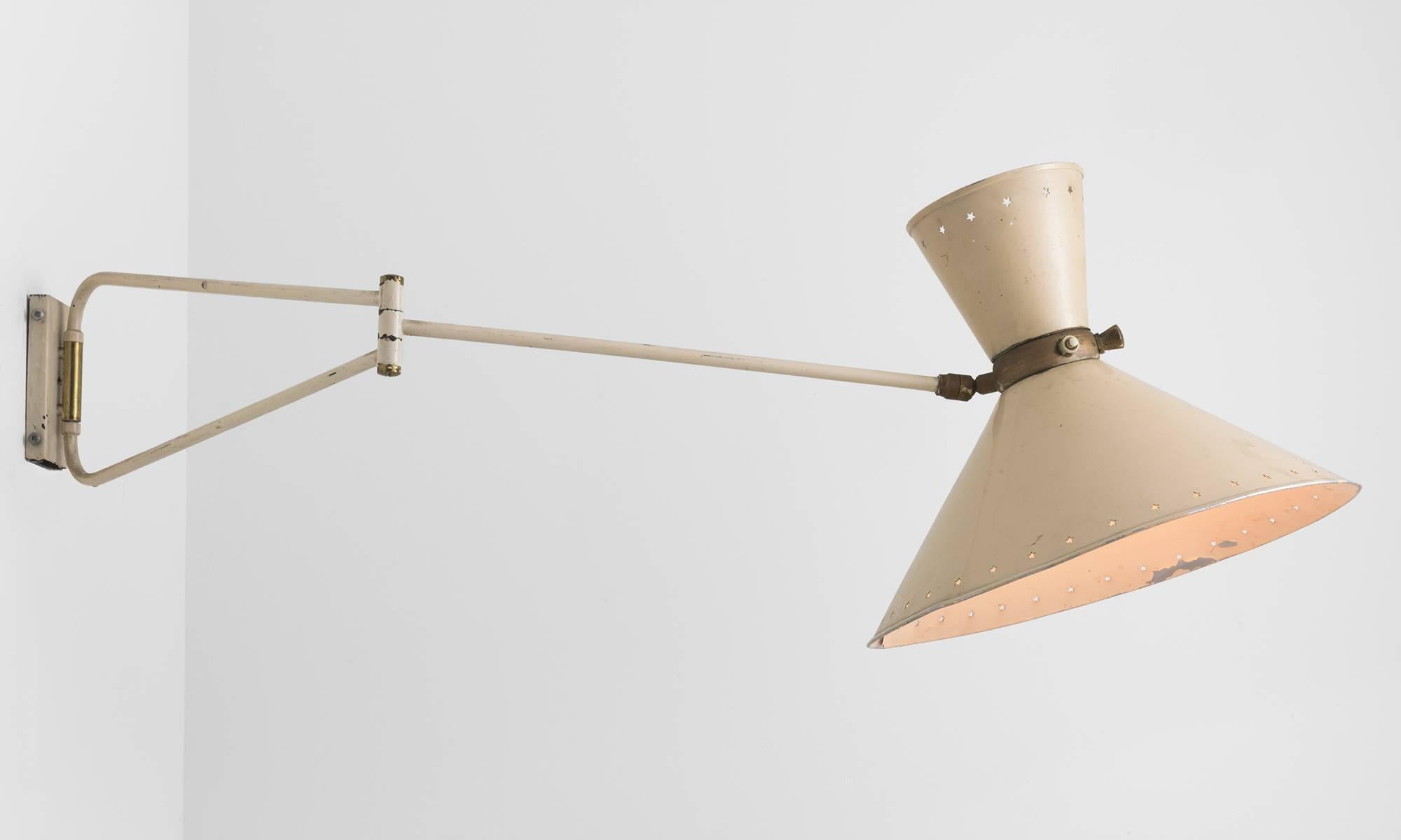 Modern swing arm wall sconce by Rene Mathieu, circa 1950.

Designed by Rene Mathieu for Lunel, France, circa 1950. Double cone lampshade with star-shaped perforation, original cream colored paint and brass details.
