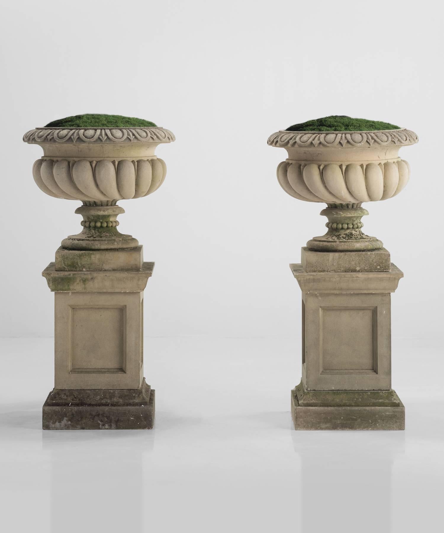 Pair of Large Westonbirt urns with pedestals, made of composite stone with beautifully weathered patina.

Made in England, circa 1975.
