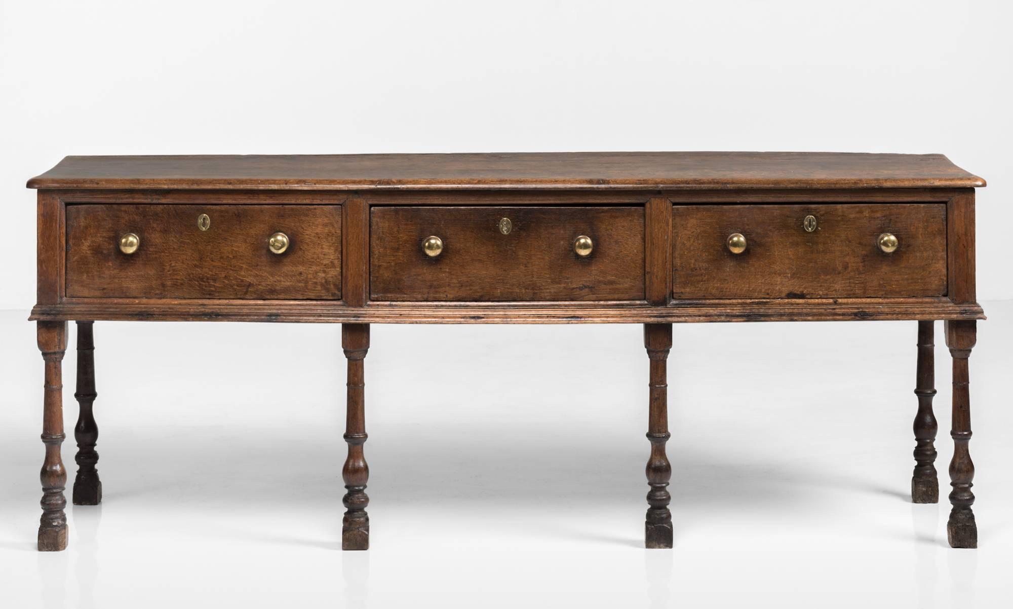 Georgian oak dresser, circa 1770.

Handsome oak dresser base, with original brass handles and moulded wait, on six turned legs.