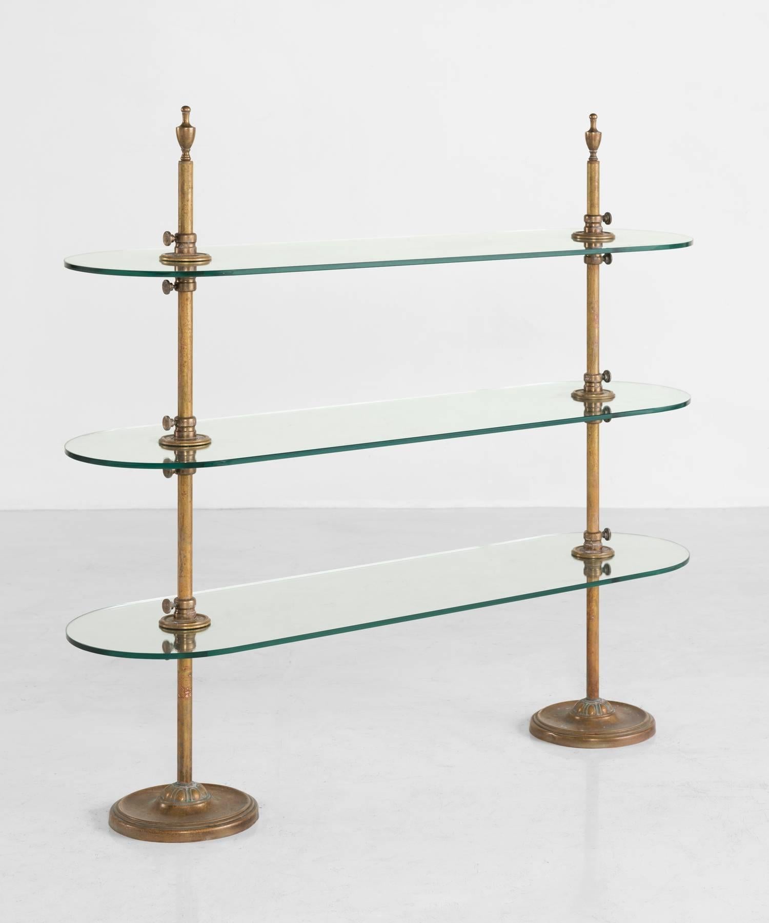 Brass and glass bistro shelving unit, circa 1910.

Adjustable brass shelving with pillar supports on circular bases accommodating three heavy clear glass shelves.