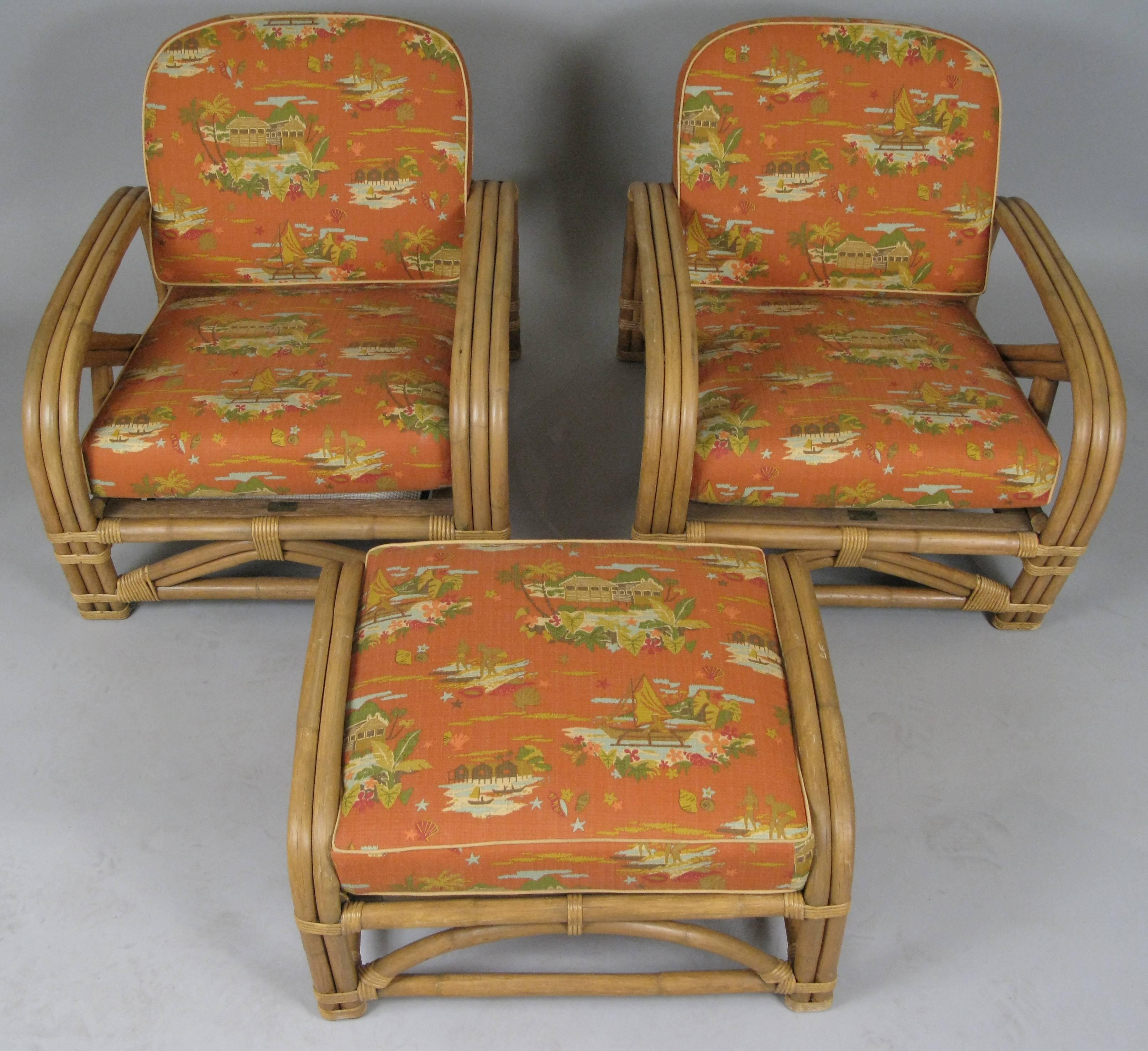 A set of Classic 1950s rattan lounge chairs with a matching ottoman by Ritts Company, complete with the original cushions covered in their original pictorial 1950s birchbark with an orange ground and tropical scenes of surfers and sailors. Very good