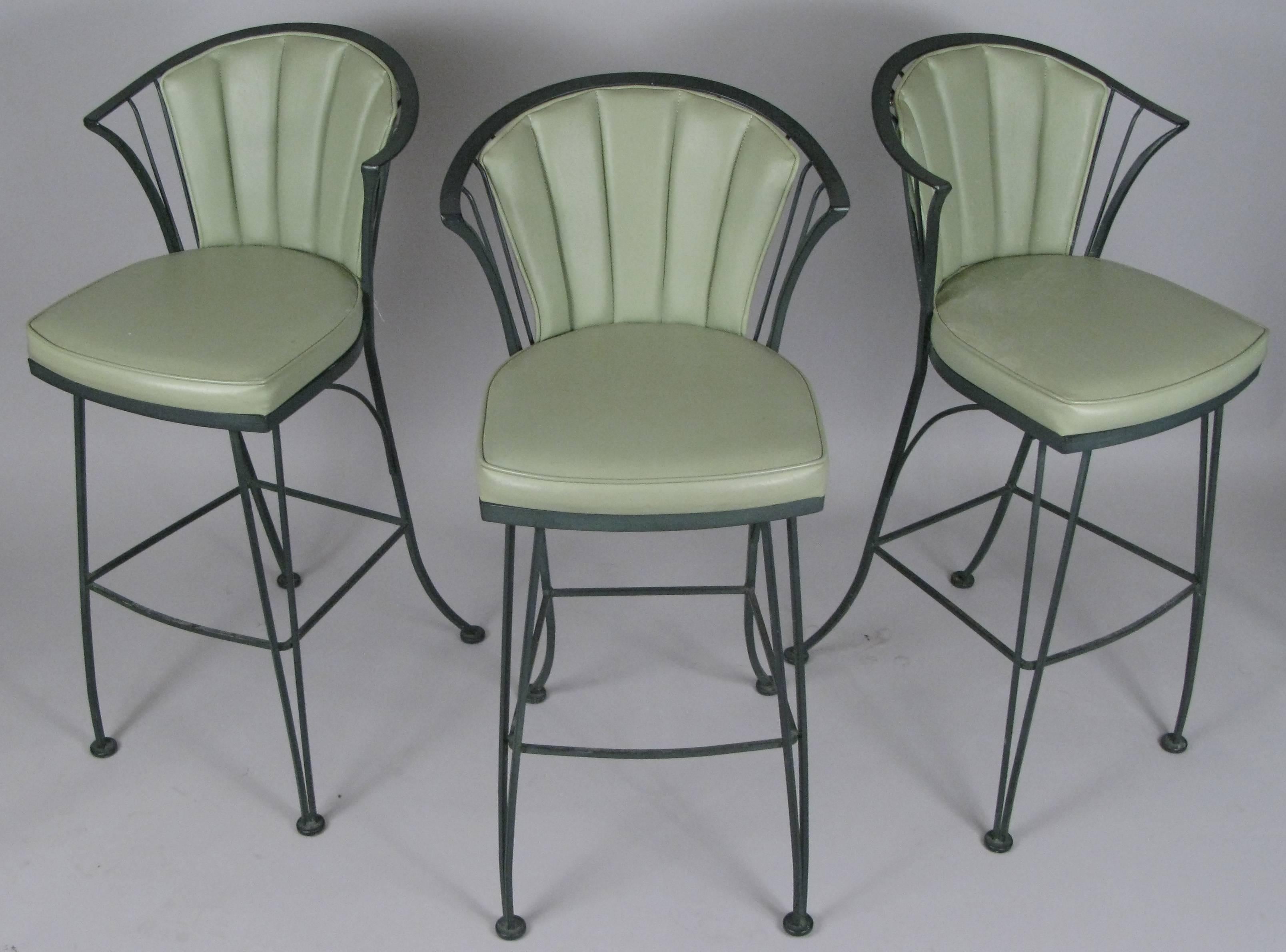 A set of three vintage 1950s wrought iron barstools from the Pinecrest collection by Woodard. Beautiful stylish design with curved legs and back and original seat and back cushions in green vinyl.