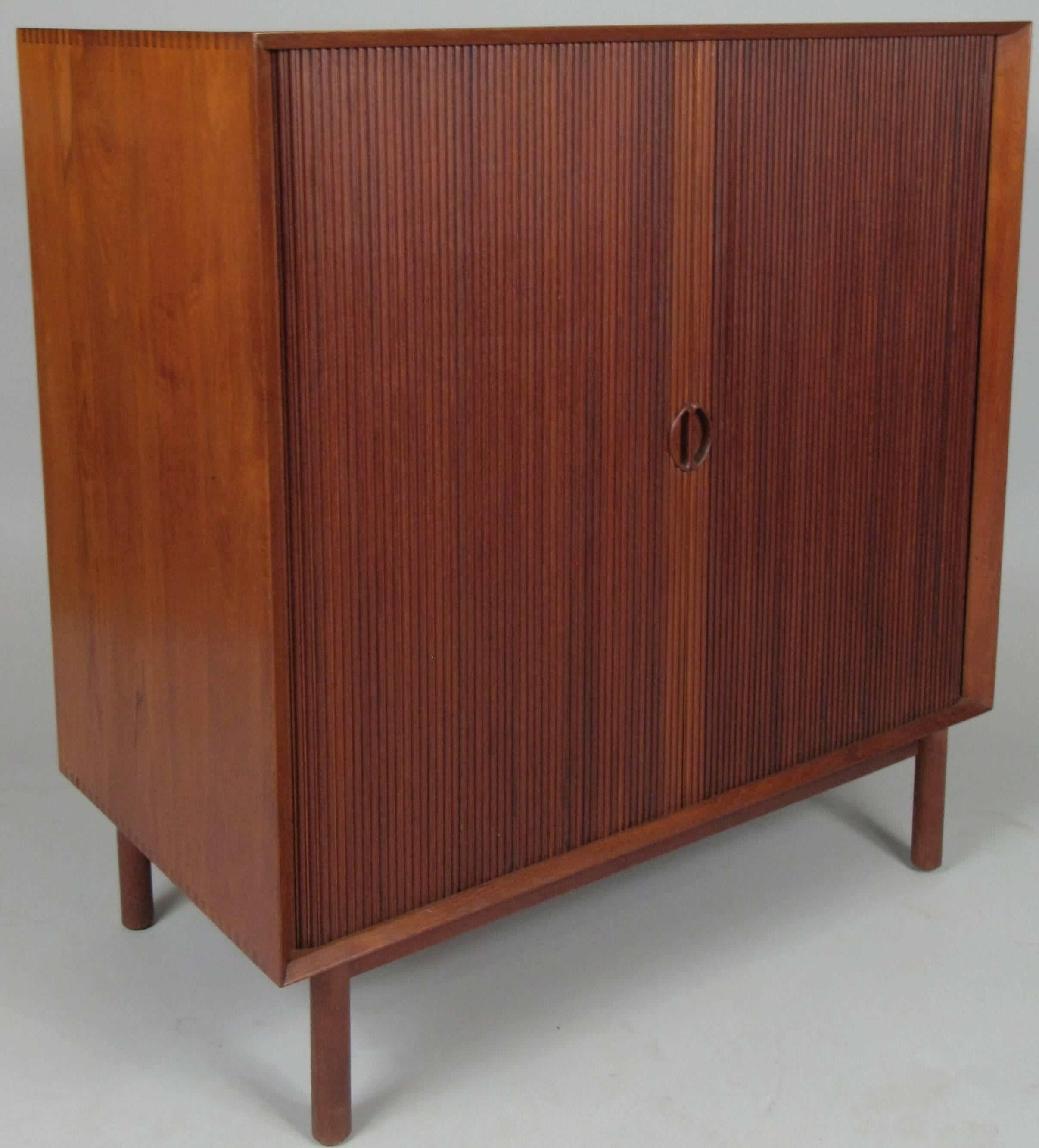 A beautiful vintage 1950s chest designed by Peter Hvidt and Orla Nielsen in solid teak, with a very nice pair of tambour doors concealing a pair of adjustable shelves. very well made and designed with dovetail joinery at the edges of the case.