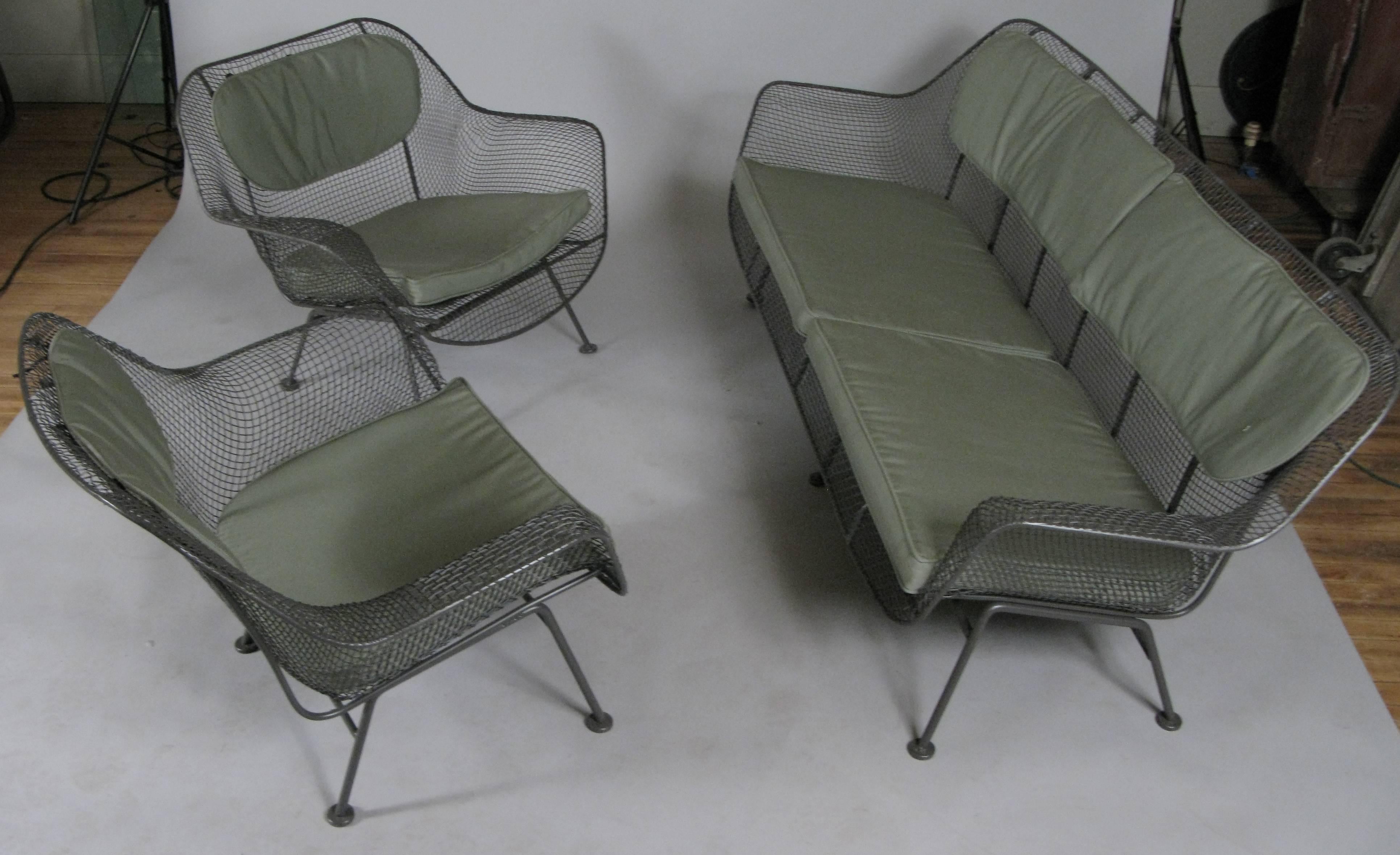A set of Sculptura lounge seating by Russell Woodard, circa 1950. Set includes a long sofa, and a pair of large lounge chairs. Woodard's iconic Sculptura collection is designed with wrought iron frames and woven steel mesh. The set is finished in an