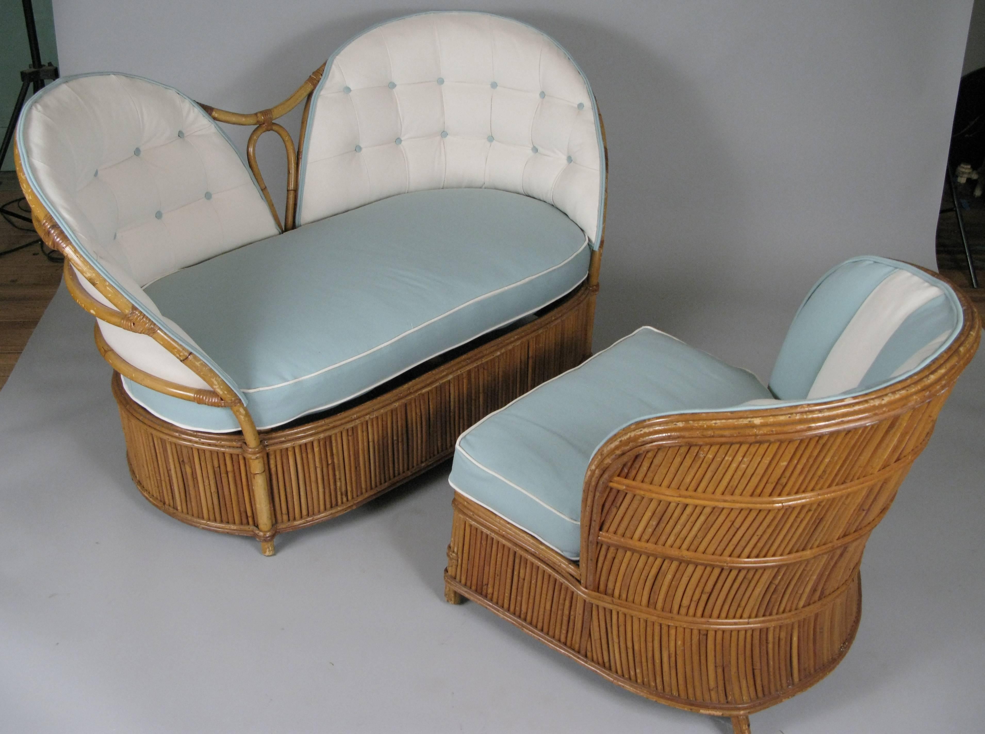 An extremely charming vintage 1940s reeded rattan settee and matching lounge chair with new upholstery in a very nice pattern of box quilting with contrasting buttons on the settee and vertical channel upholstery on the chair. Frames are in vintage