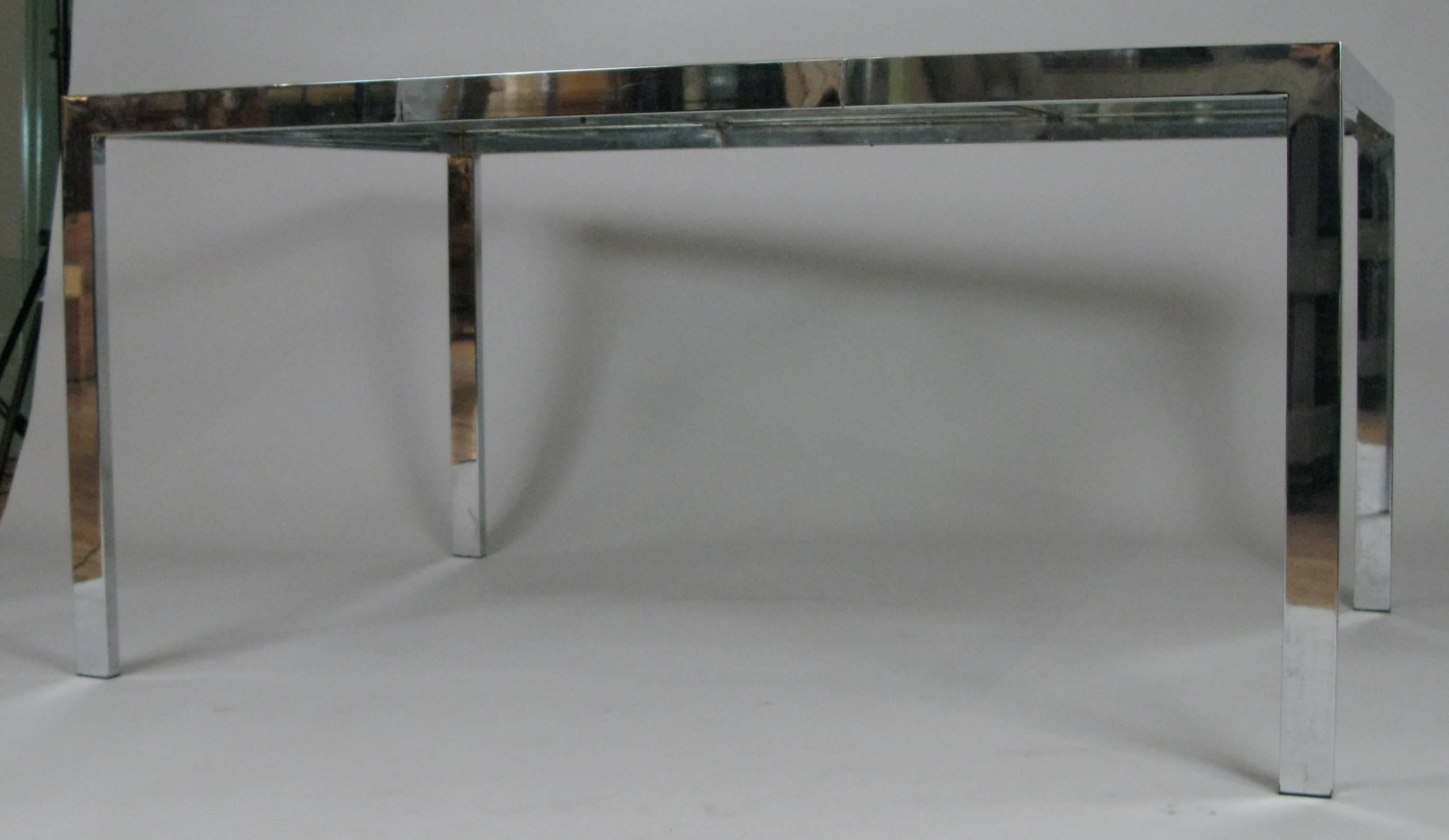 A beautiful vintage 1970s extension dining table with a chromed steel frame and glass top with chrome frame as well. The table starts out as a square and slides apart to accommodate a glass leaf with the same chrome trim. Very nice design and in