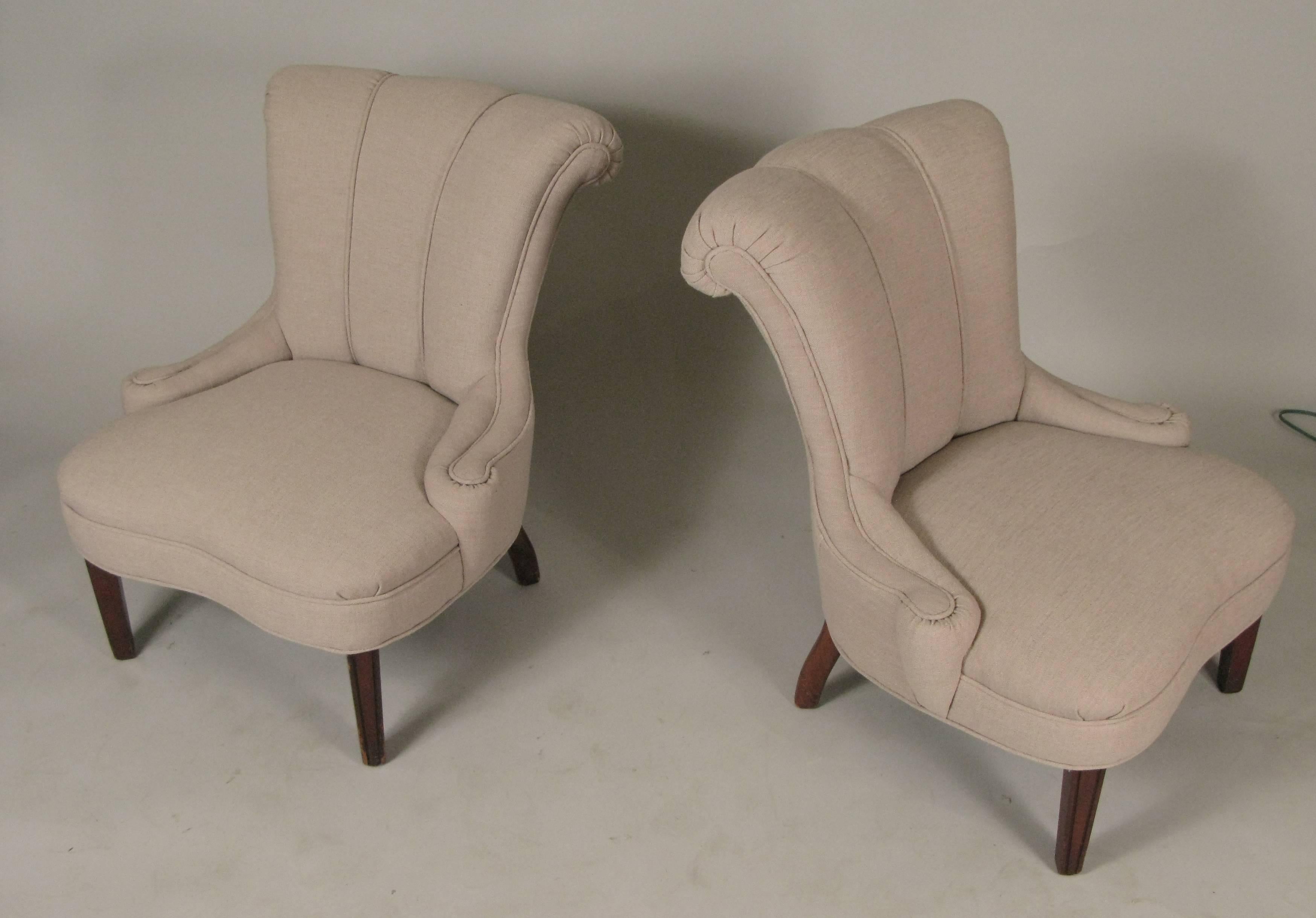A very charming pair of 1940s slipper chairs with beautiful curved backs with rolled detail at the top and raised on mahogany legs. graceful lines and just expertly reupholstered in a very nice beige textured fabric.