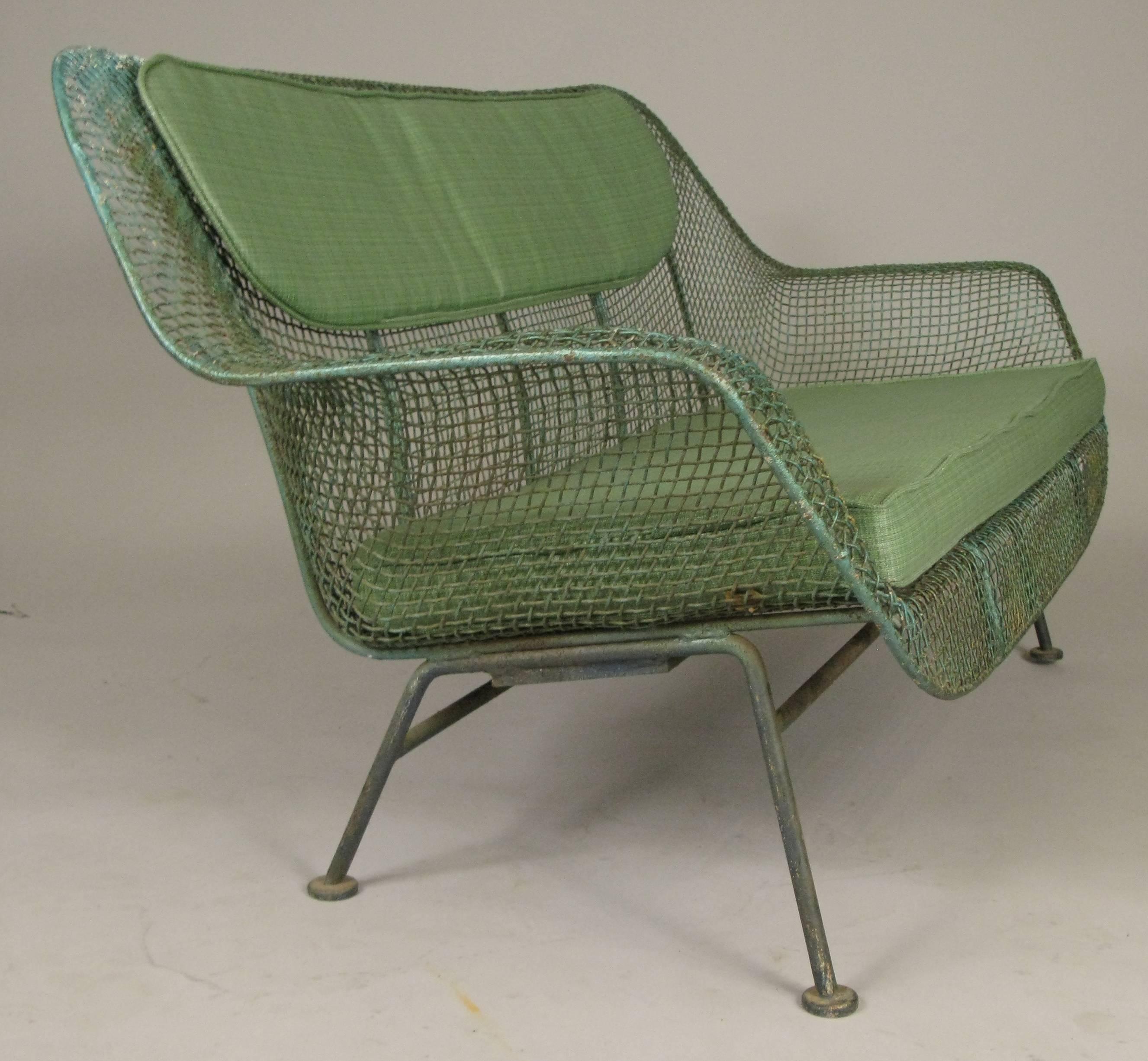 A vintage 1950s wrought iron and steel mesh settee from Russell Woodard's Classic and iconic sculptura series. Beautiful and Classic sculptural design, in its original forest green weathered painted finish, with a set of rare original cushions also