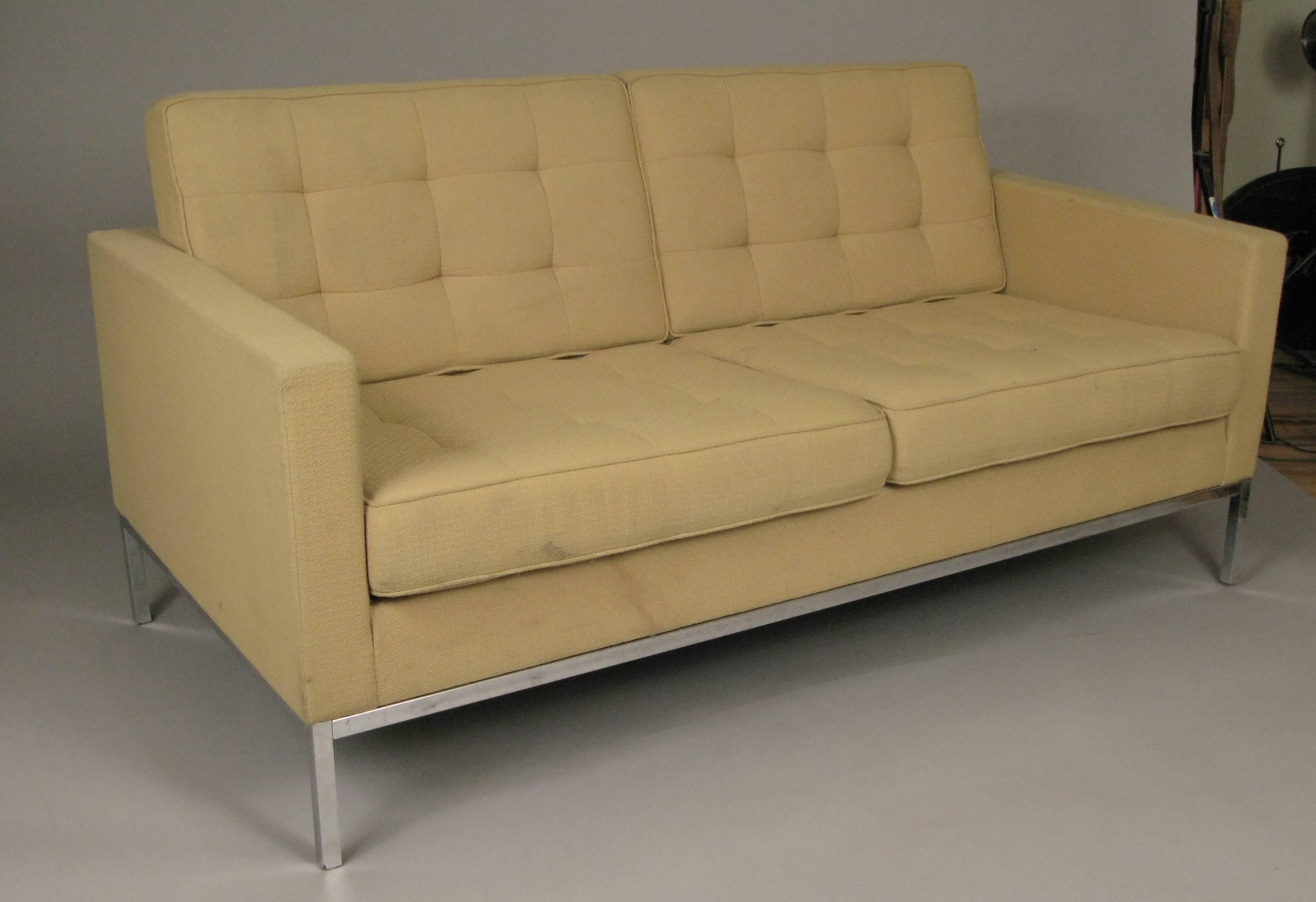 A vintage chrome base two seat settee designed by Florence Knoll for Knoll International, with box quilted upholstery, which is in original condition with light wear and some stains.