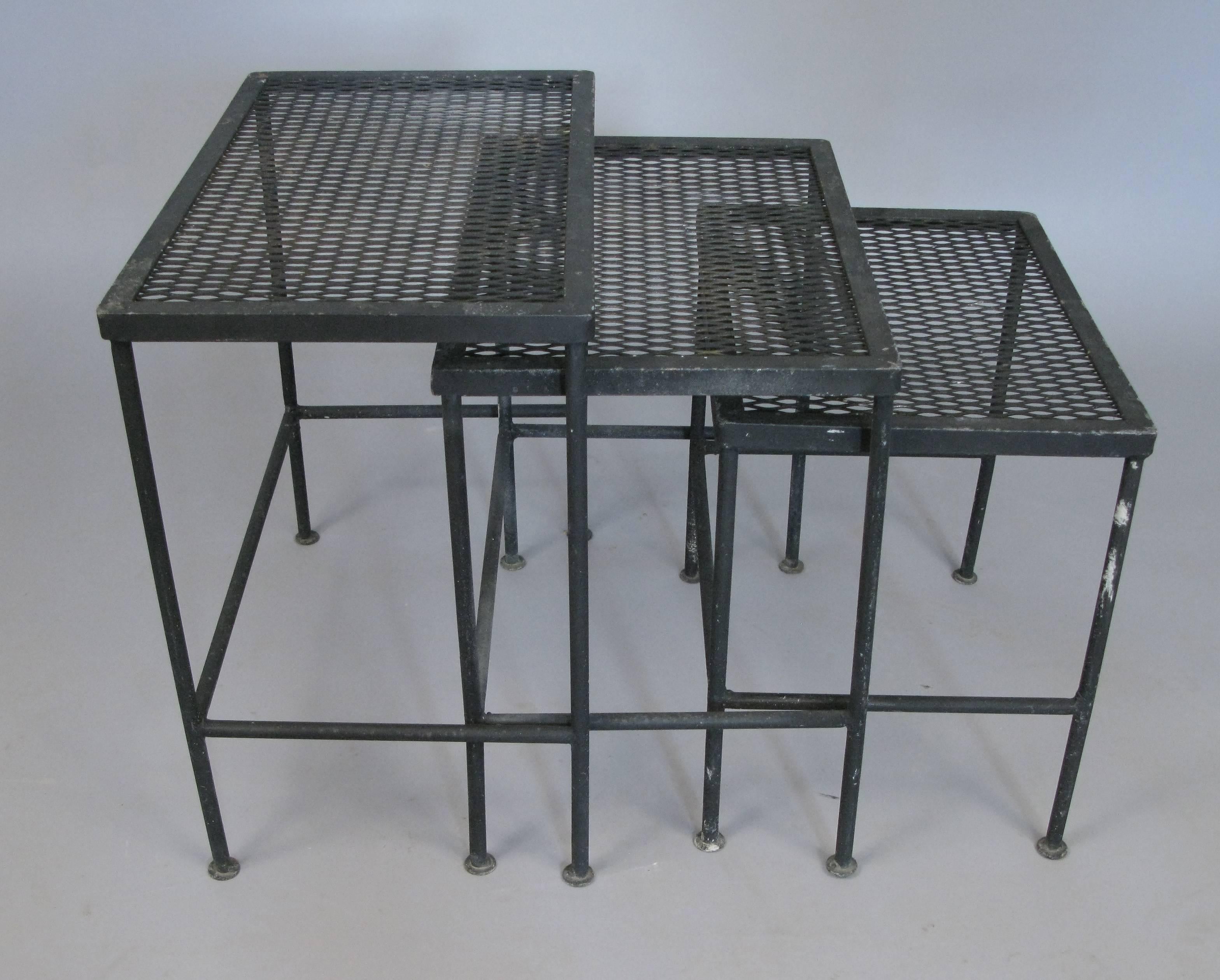 A rare set of vintage 1950s wrought iron nesting tables by Woodard, rectangular in form with steel mesh tops and wrought iron stretchers. Very good original condition.