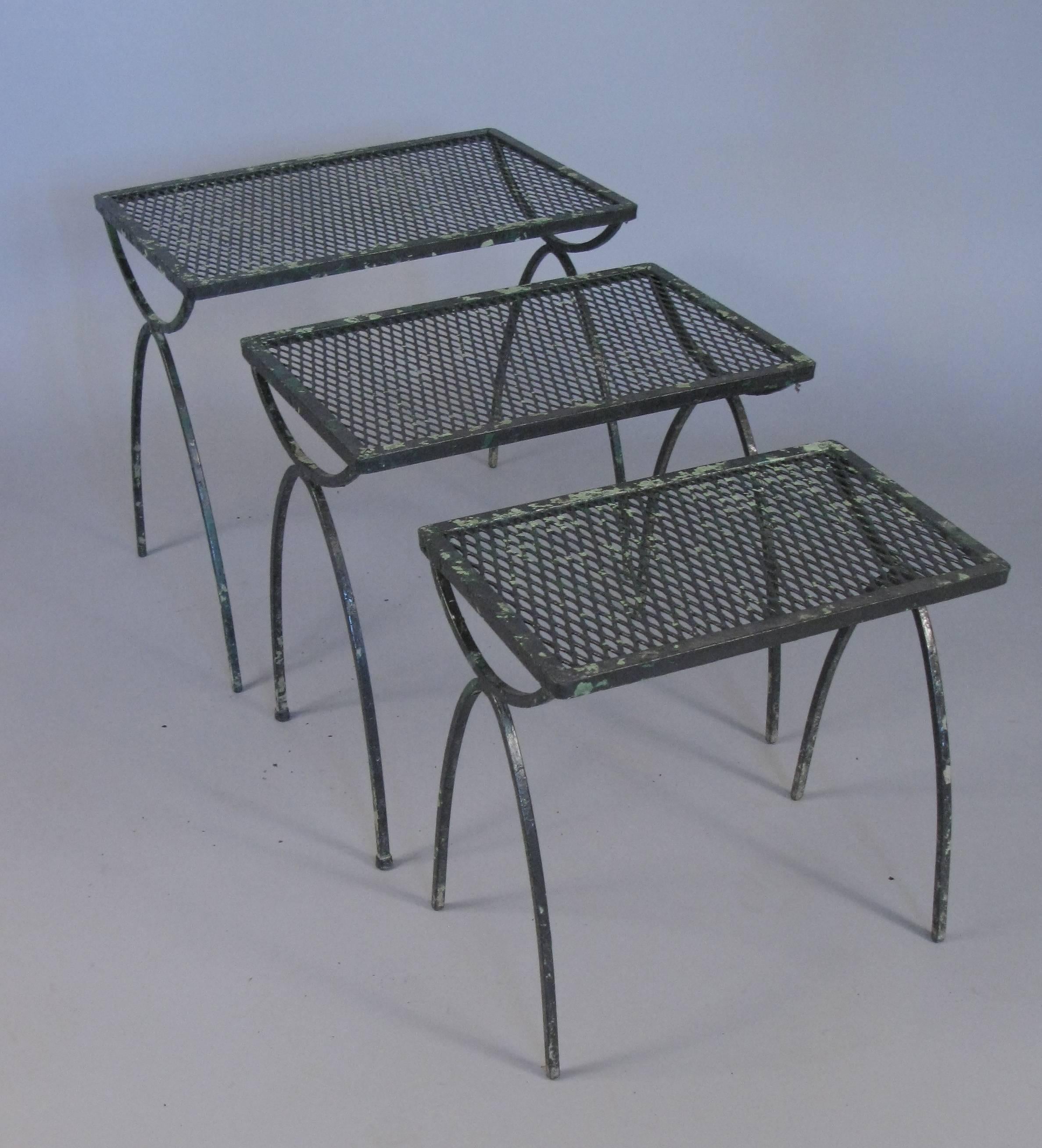 A set of three vintage 1950s wrought iron nesting tables by Salterini from the radar collection. Rectangular surfaces with tall curved legs, they go perfectly with a variety of vintage garden furniture. They are in a black finish over several layers