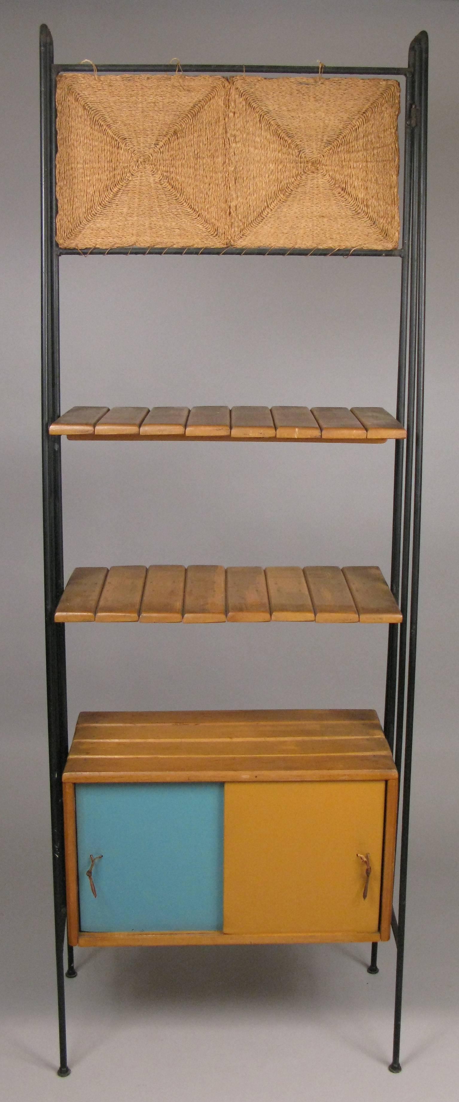 A rare vintage 1950s freestanding etagere or bar cabinet designed by Arthur Umanoff. having a wrought iron frame, and lower storage cabinet with color block sliding panel doors on both front and back, and two birch shelves, along with a decorative