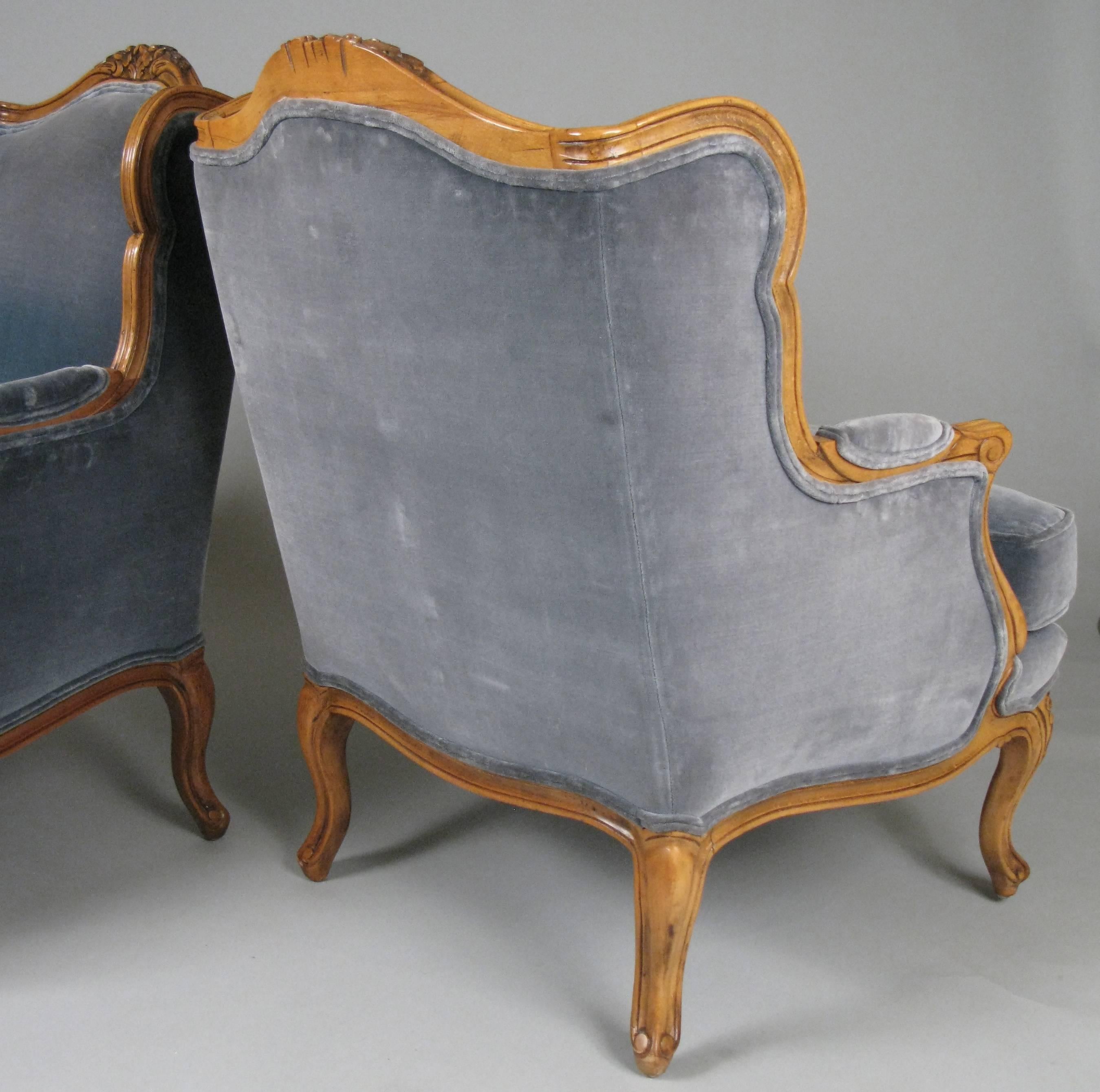 A charming pair of vintage 1950s French style bergère armchairs by Baker, in their original medium blue velvet upholstery and natural fruitwood frames.