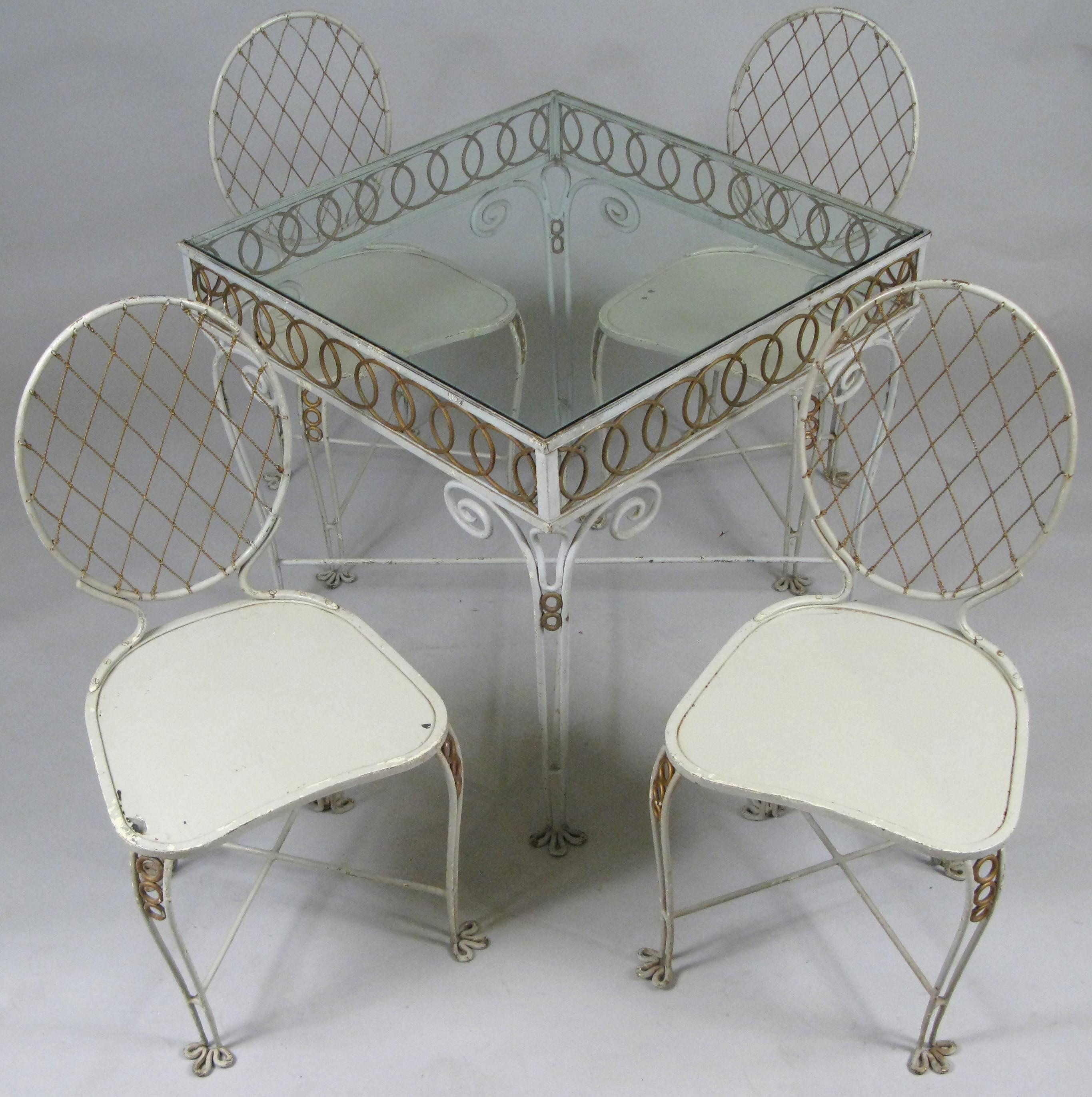 An absolutely charming vintage 1940s dining set with wrought iron frames and gold painted details. The chair backs made with twisted gilded wire in a lattice formation. The details are beautiful, including the flower form feet on the chairs and