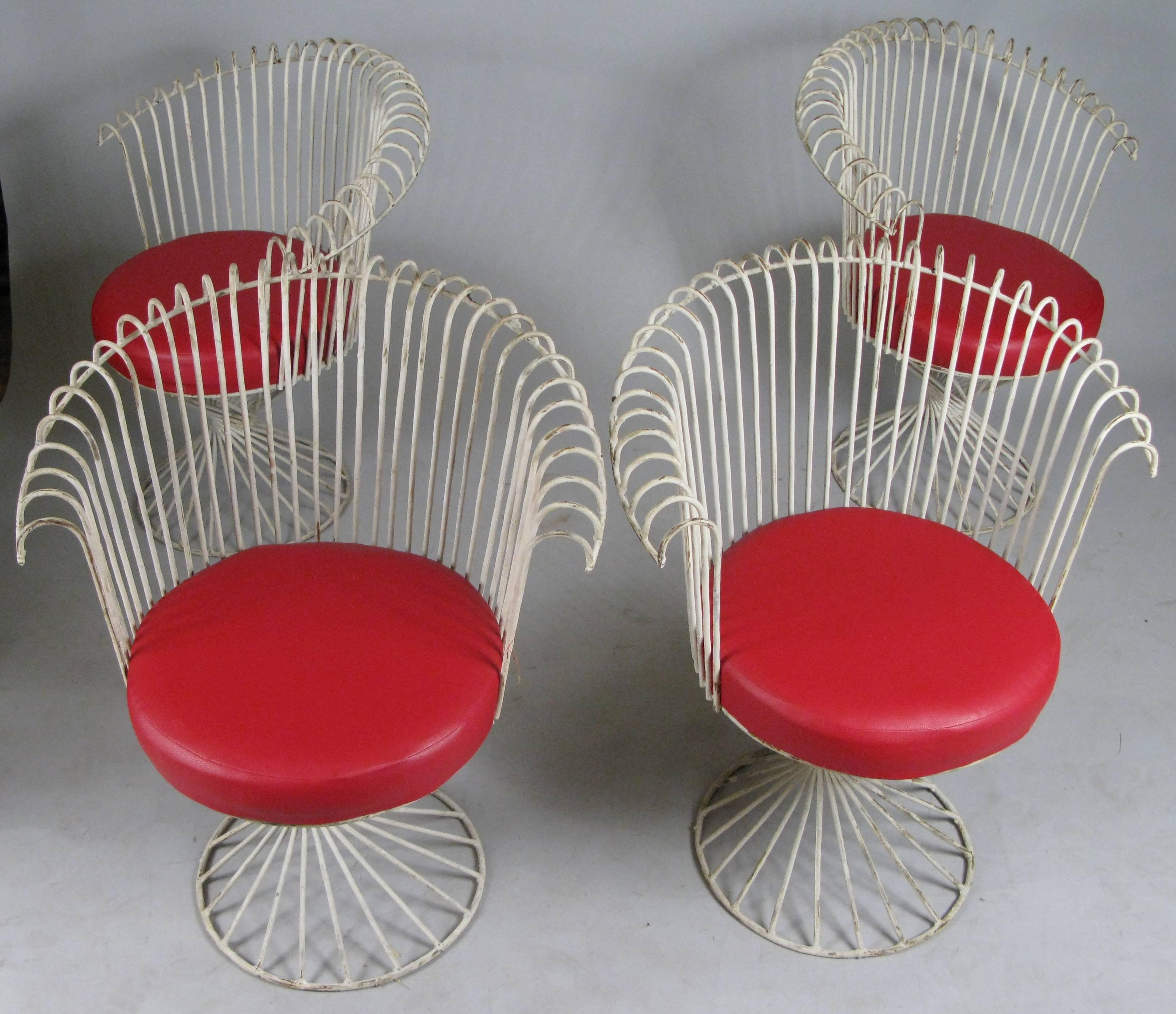 A lovely set of four curved wrought iron garden chairs in the manner of Mathieu Mategot. Beautifully made with the original white painted finish in fair condition and red vinyl seat cushions.
