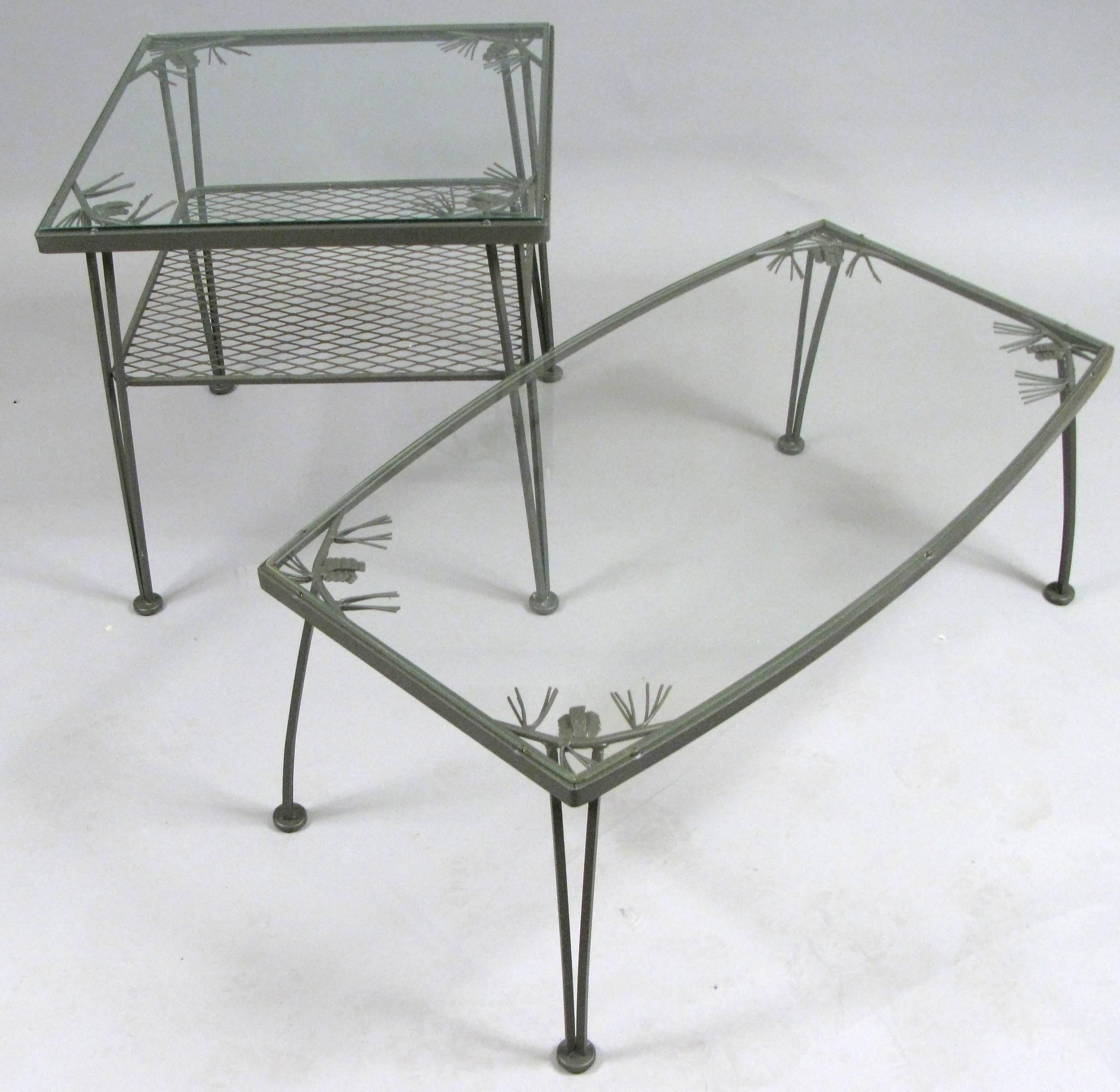 A companion pair of vintage 1950s wrought iron occasional tables from the Pinecrest collection by Woodard. The coffee table has a lozenge shape, with a glass top, and the square side table has a glass top and a lower shelf. Both tables have the